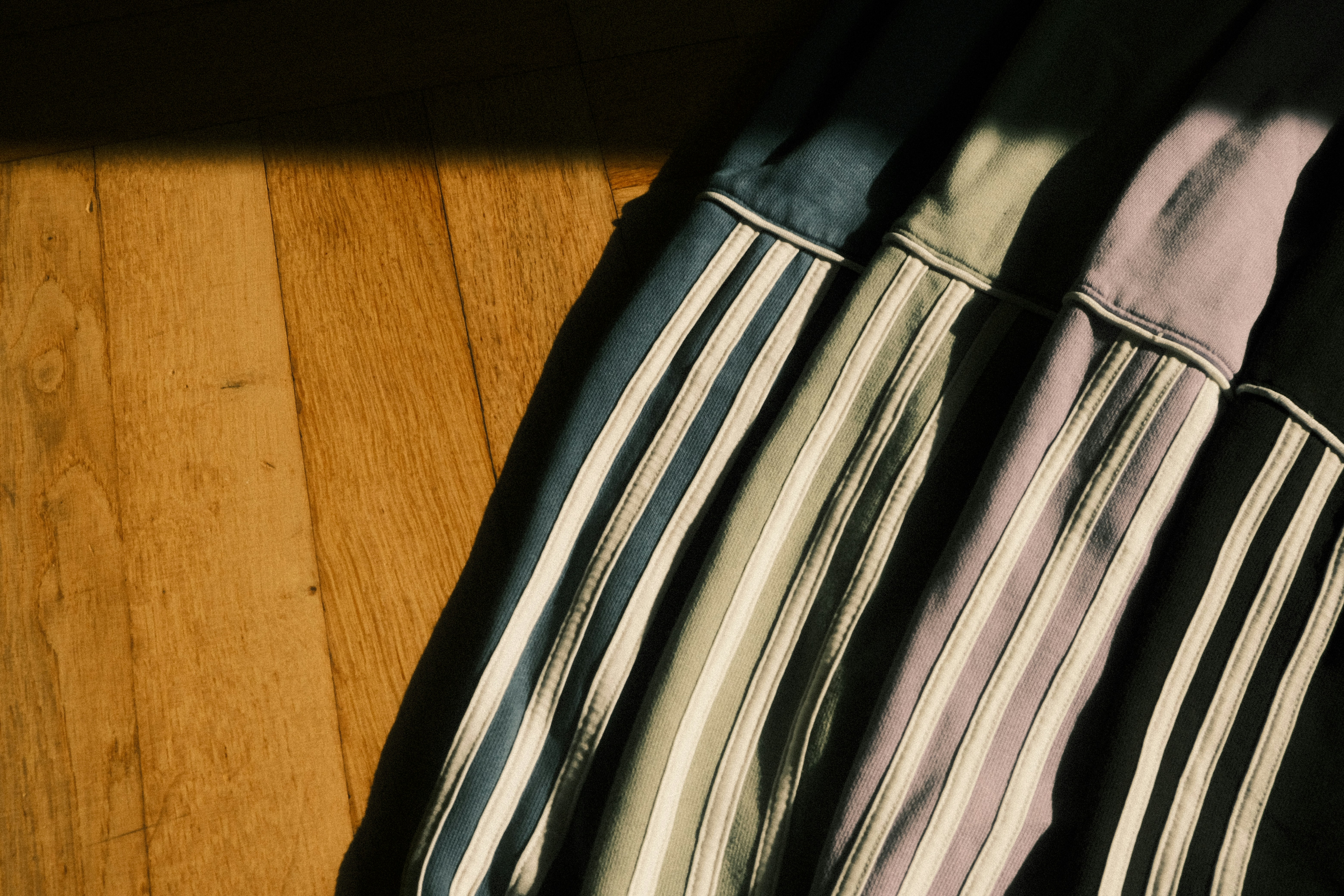 Striped fabric casts shadows on a wooden floor.