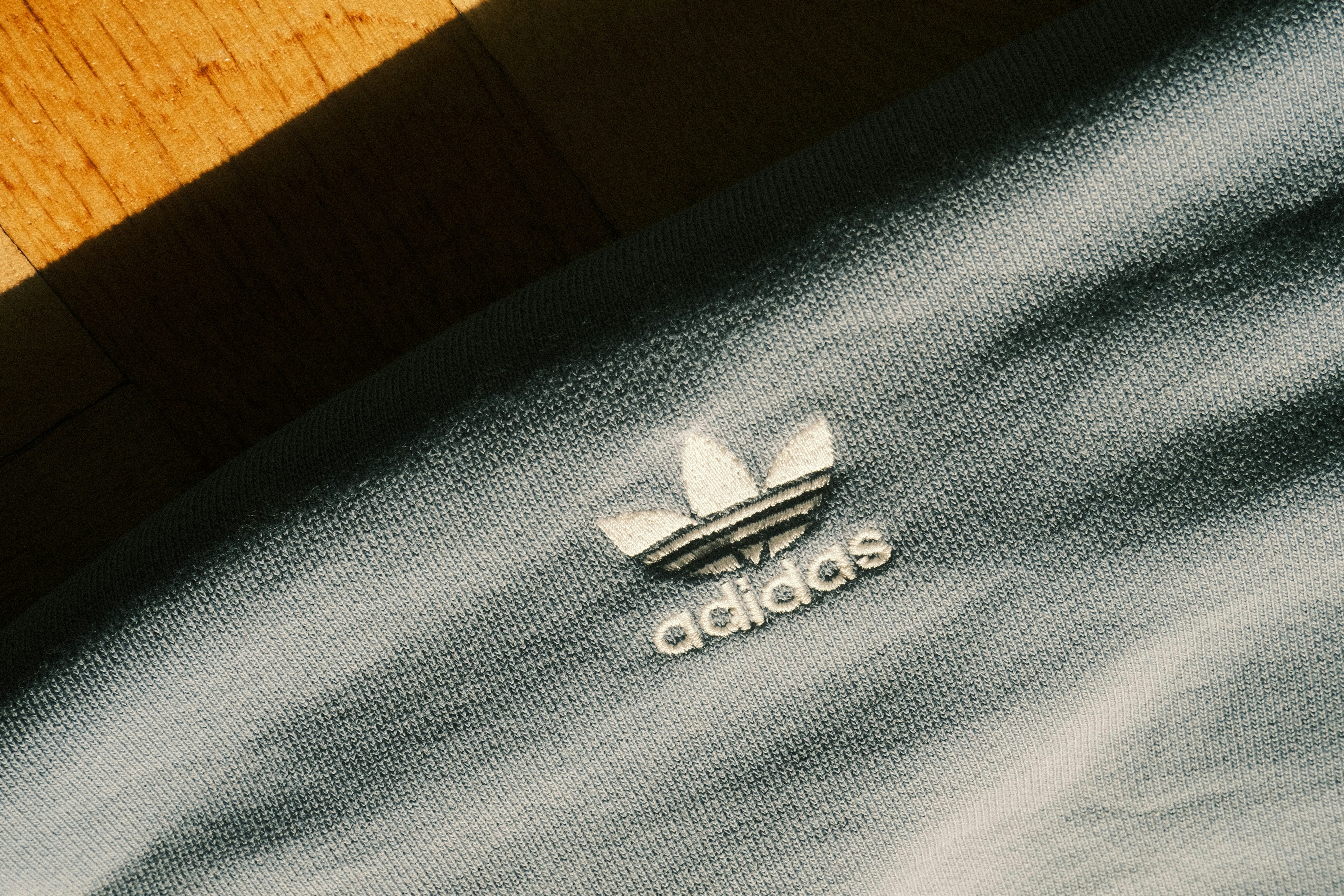 Close-up of an adidas logo on a light blue garment.