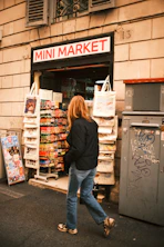 Woman walks past a mini market storefront.