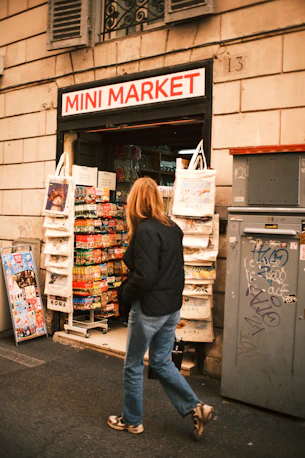 Woman walks past a mini market storefront.