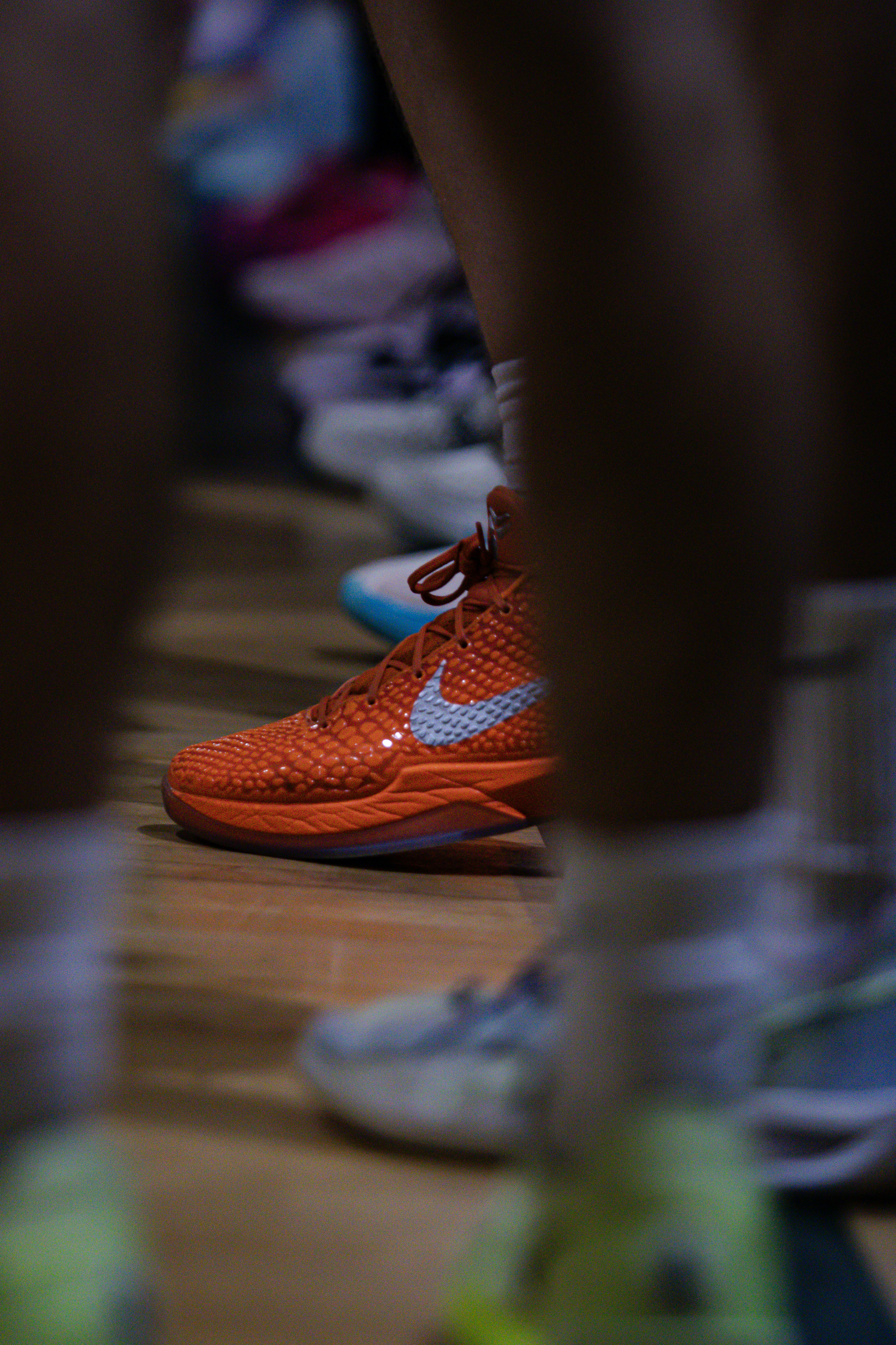 Close up of orange basketball shoes on a wooden court