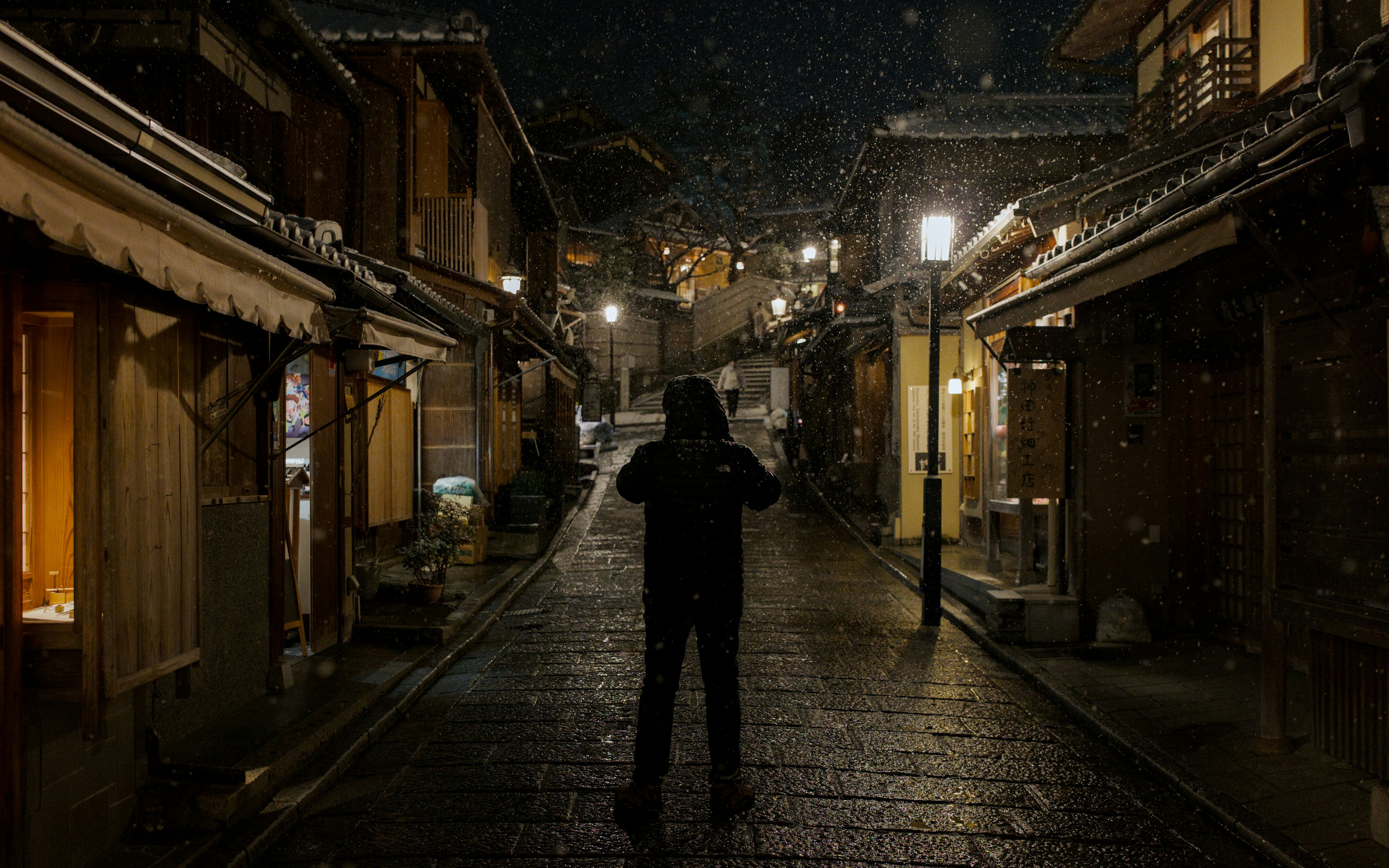 Person standing on a wet street at night