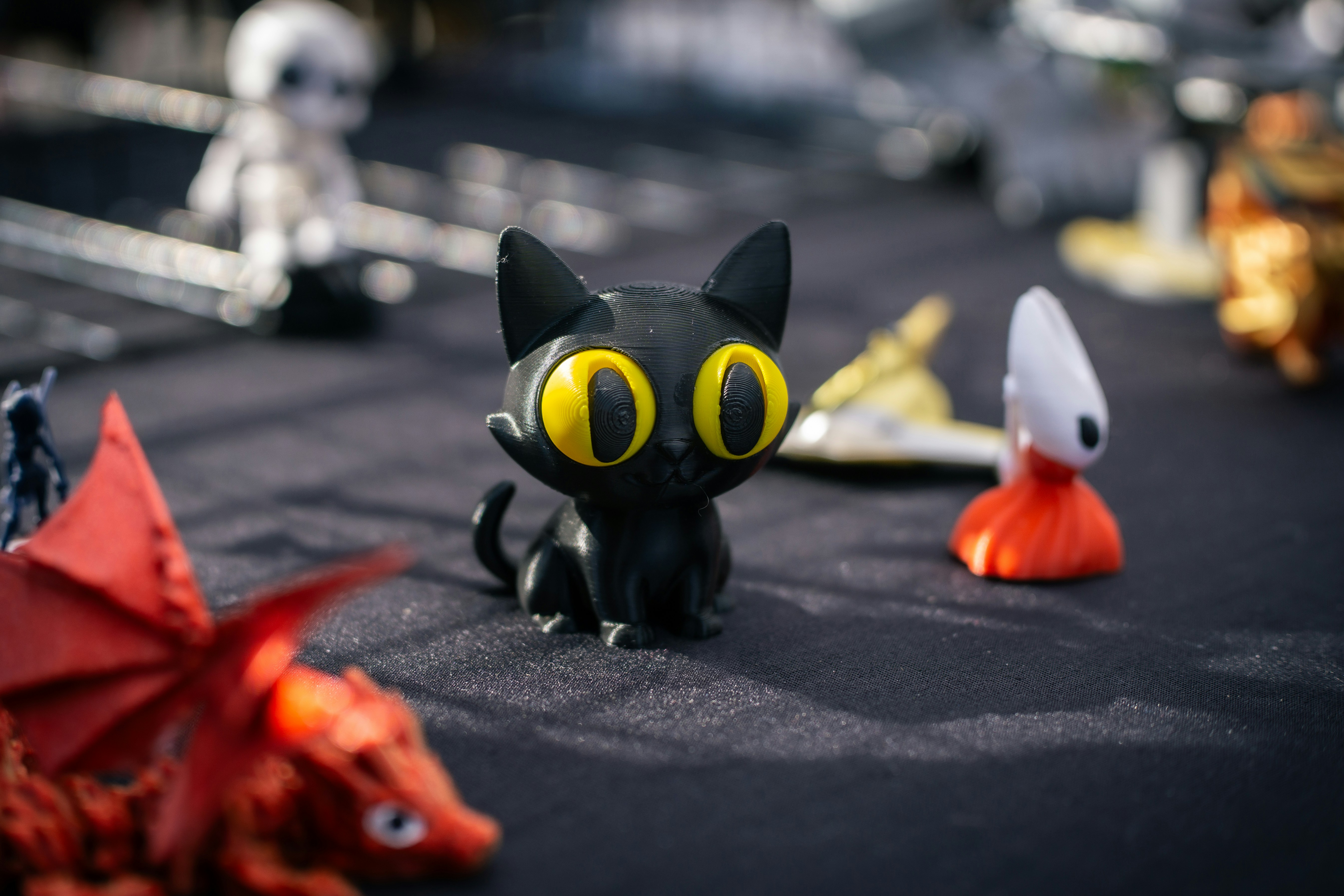 A small black cat figurine with big yellow eyes.