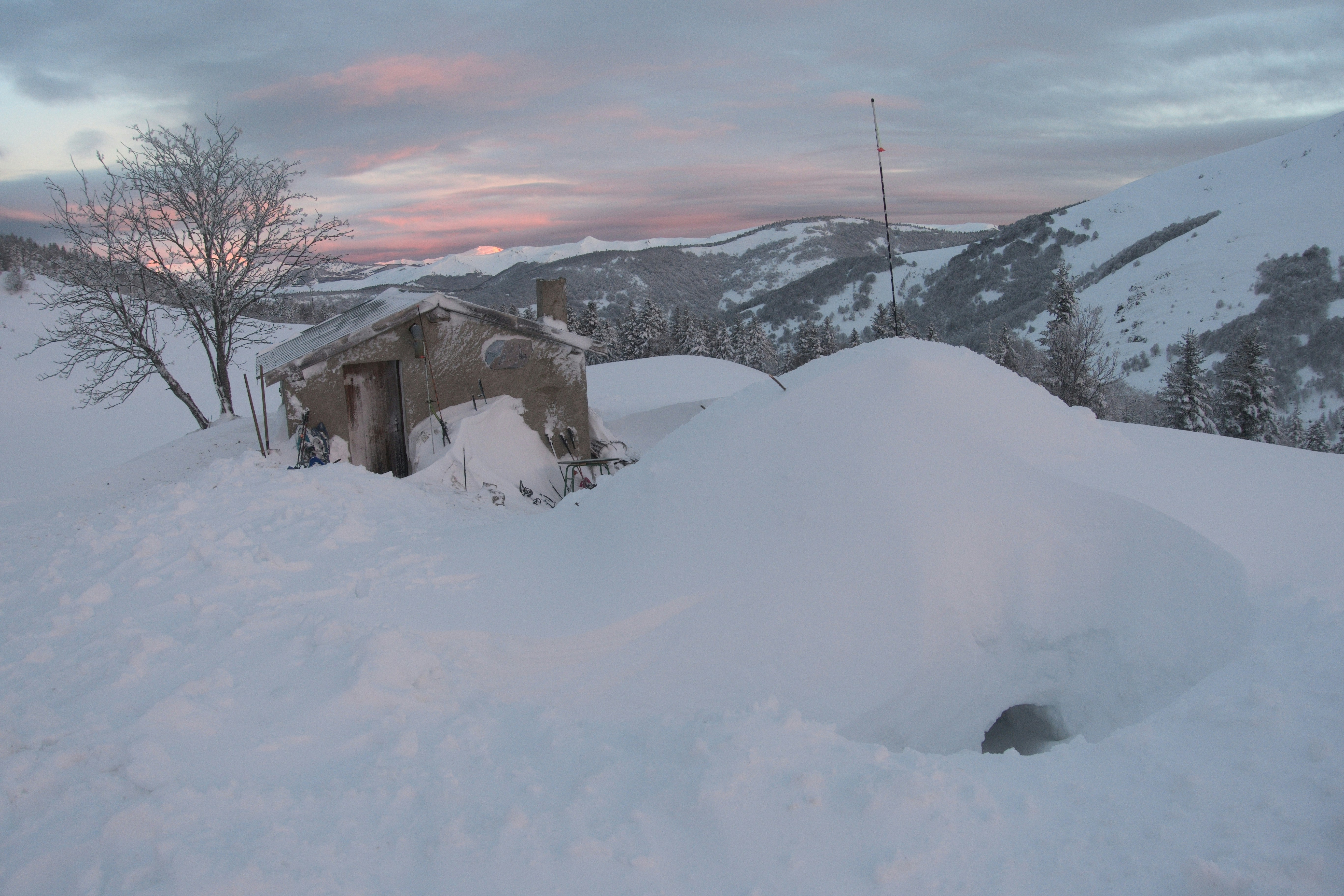 Cabane enneigée dans un paysage montagneux au crépuscule