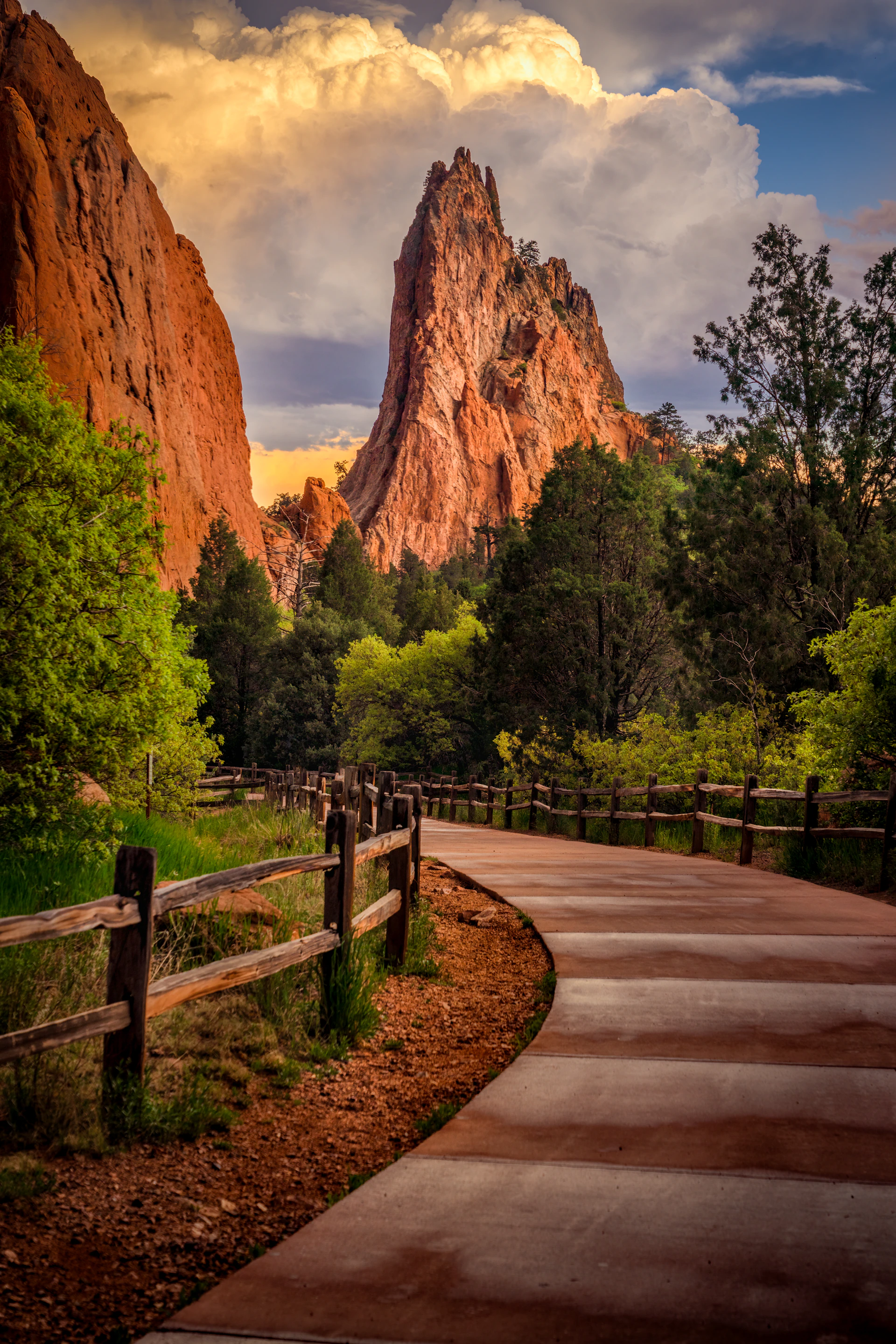 Red rock formations with a winding path and green trees.