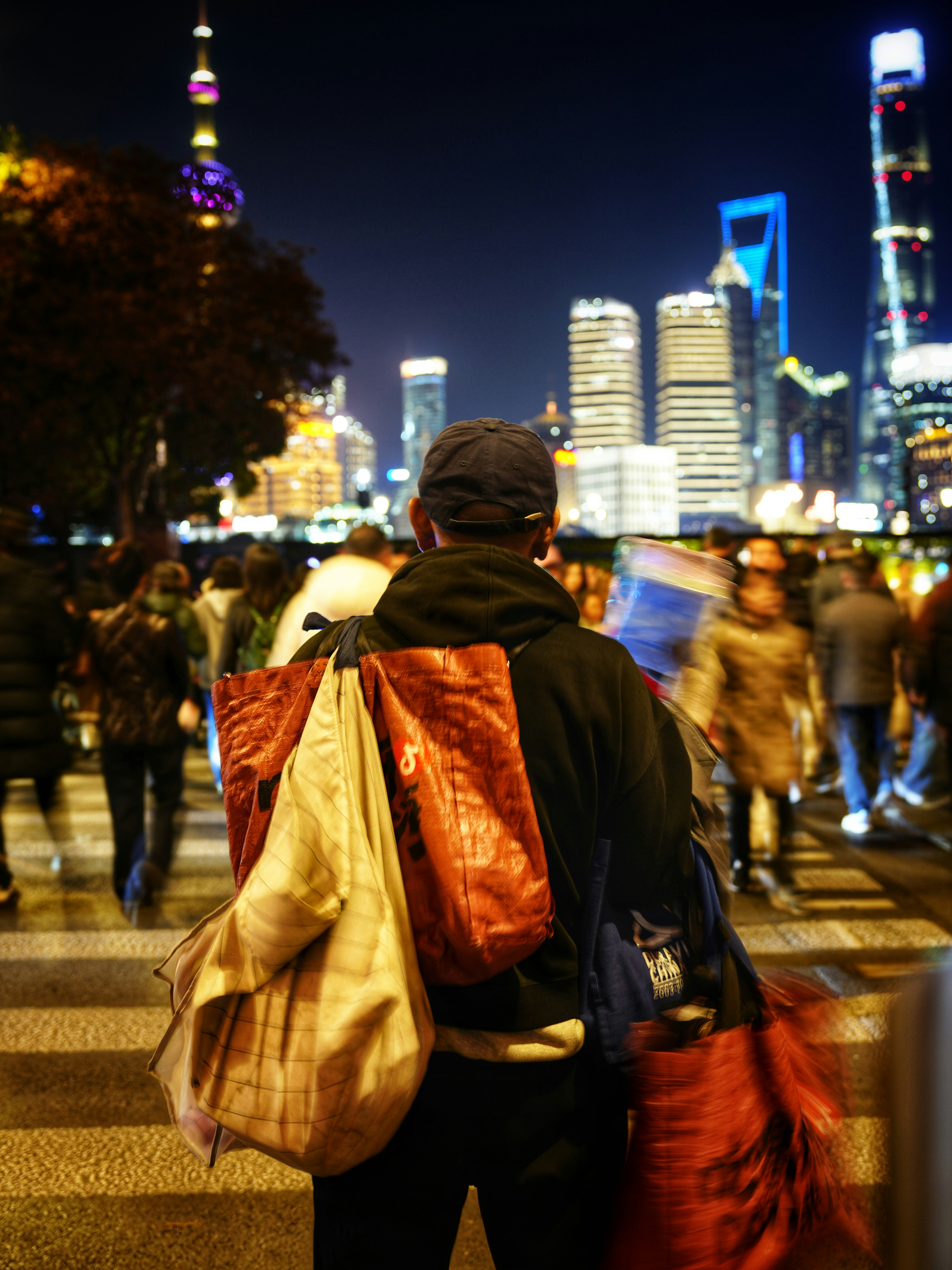 Man carrying bags across a busy city street at night
