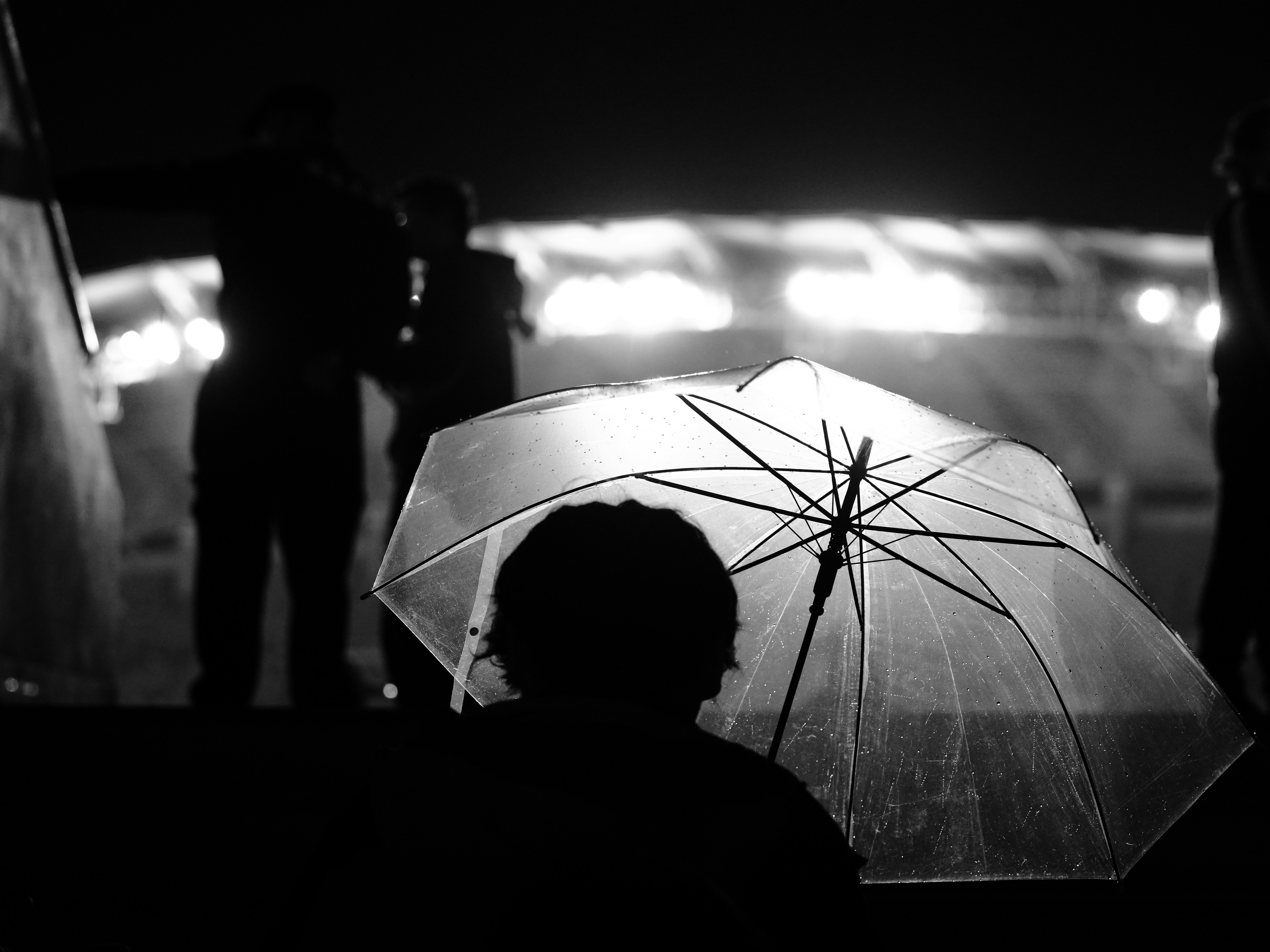 A person holding a clear umbrella at night