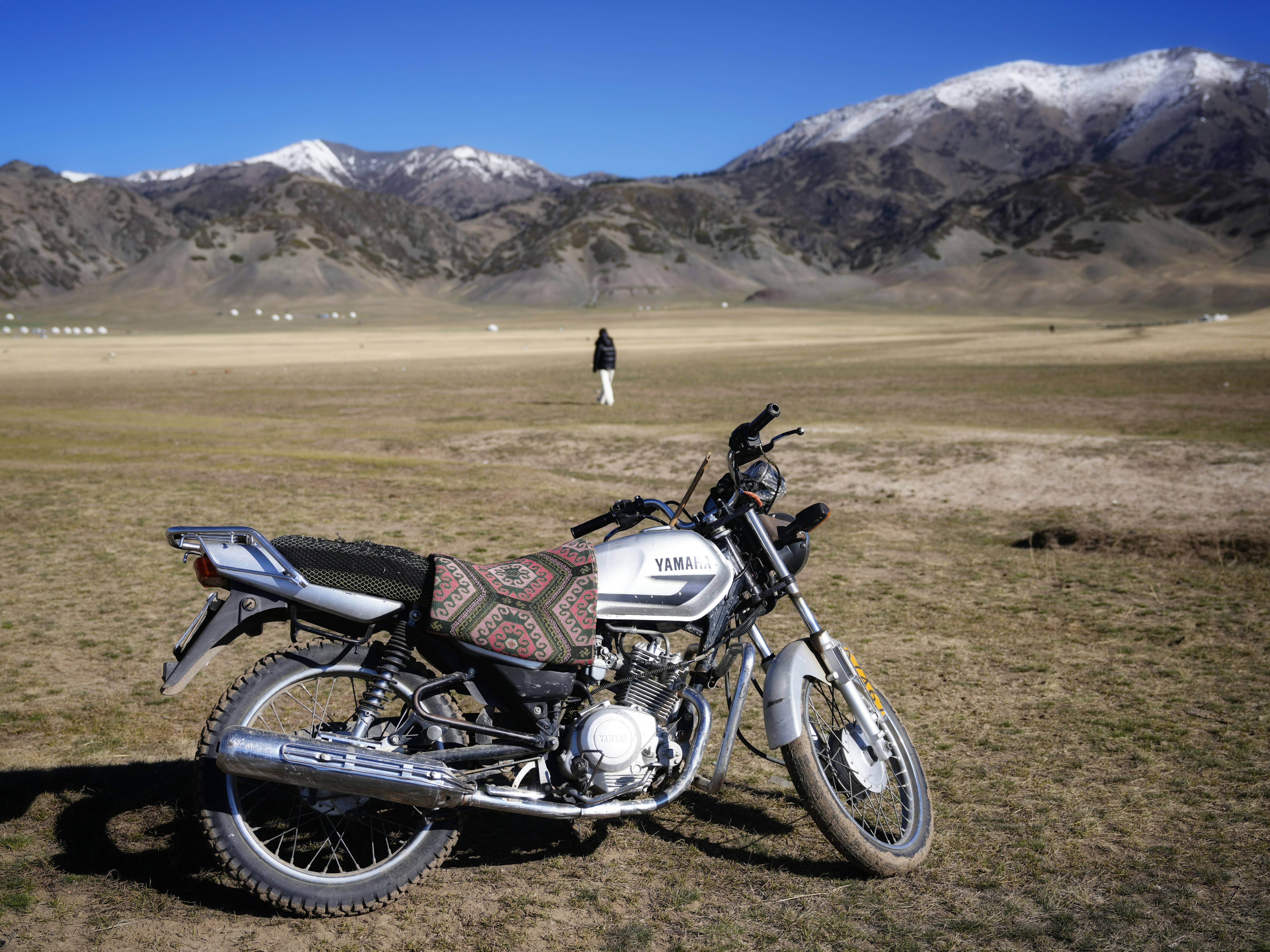 Motorcycle parked in a vast, dry landscape with mountains.