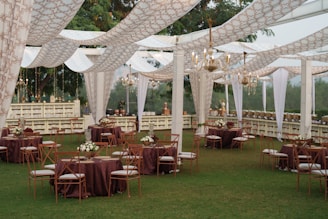 Elegant outdoor wedding reception with draped canopy and tables.