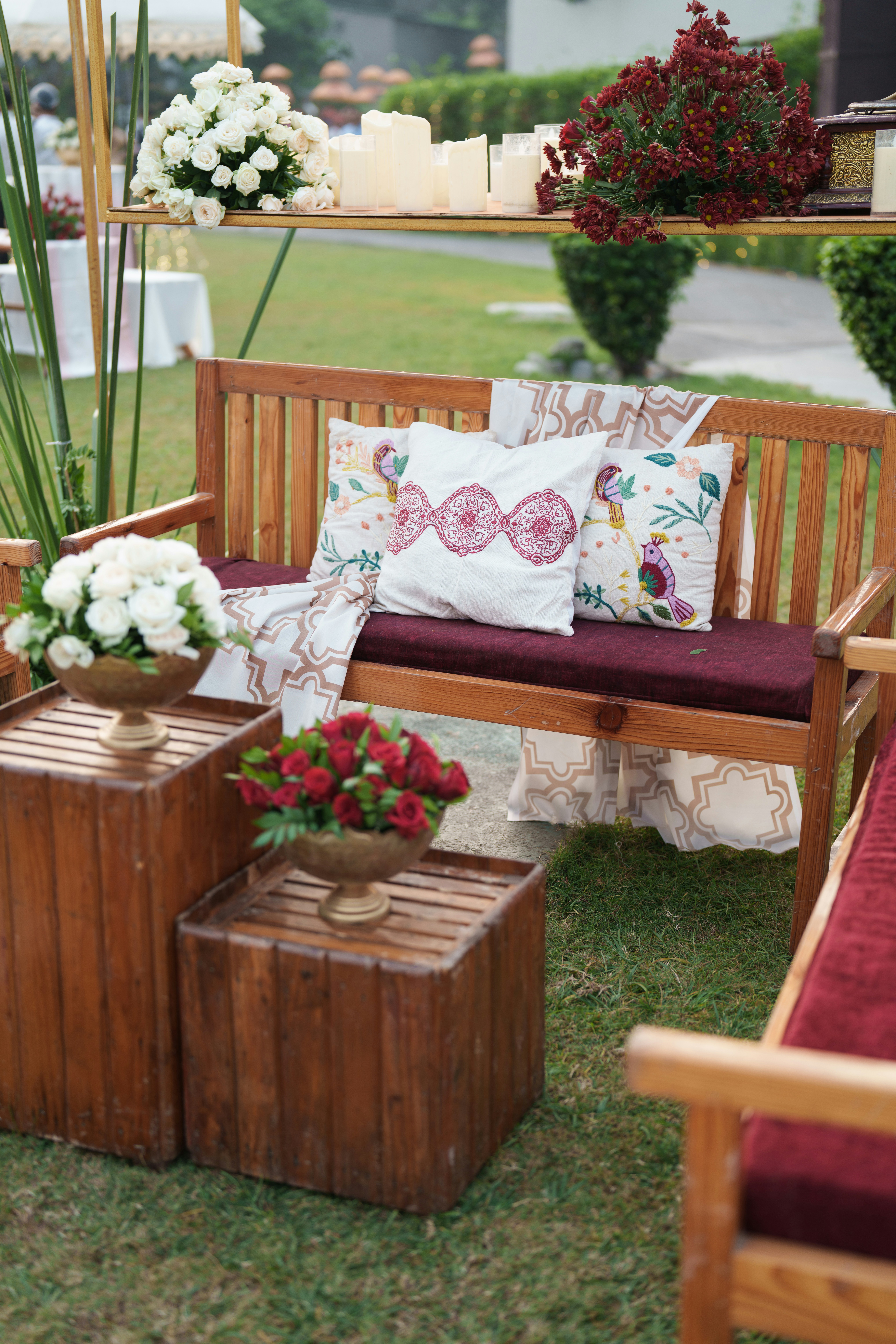 Holzbank mit dekorativen Kissen und Blumenarrangements.