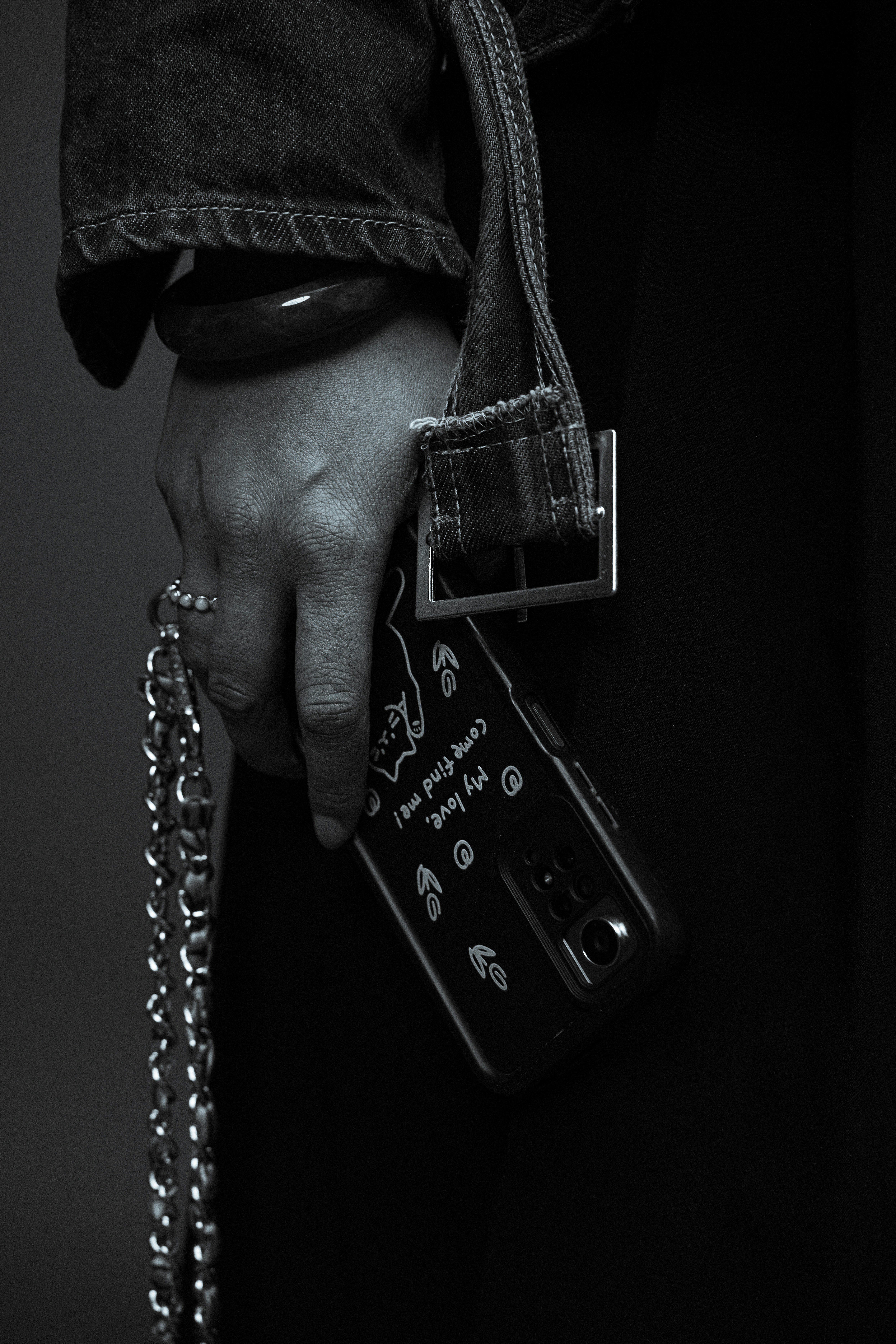 Eine Hand hält ein Smartphone mit einem Kettenriemen.