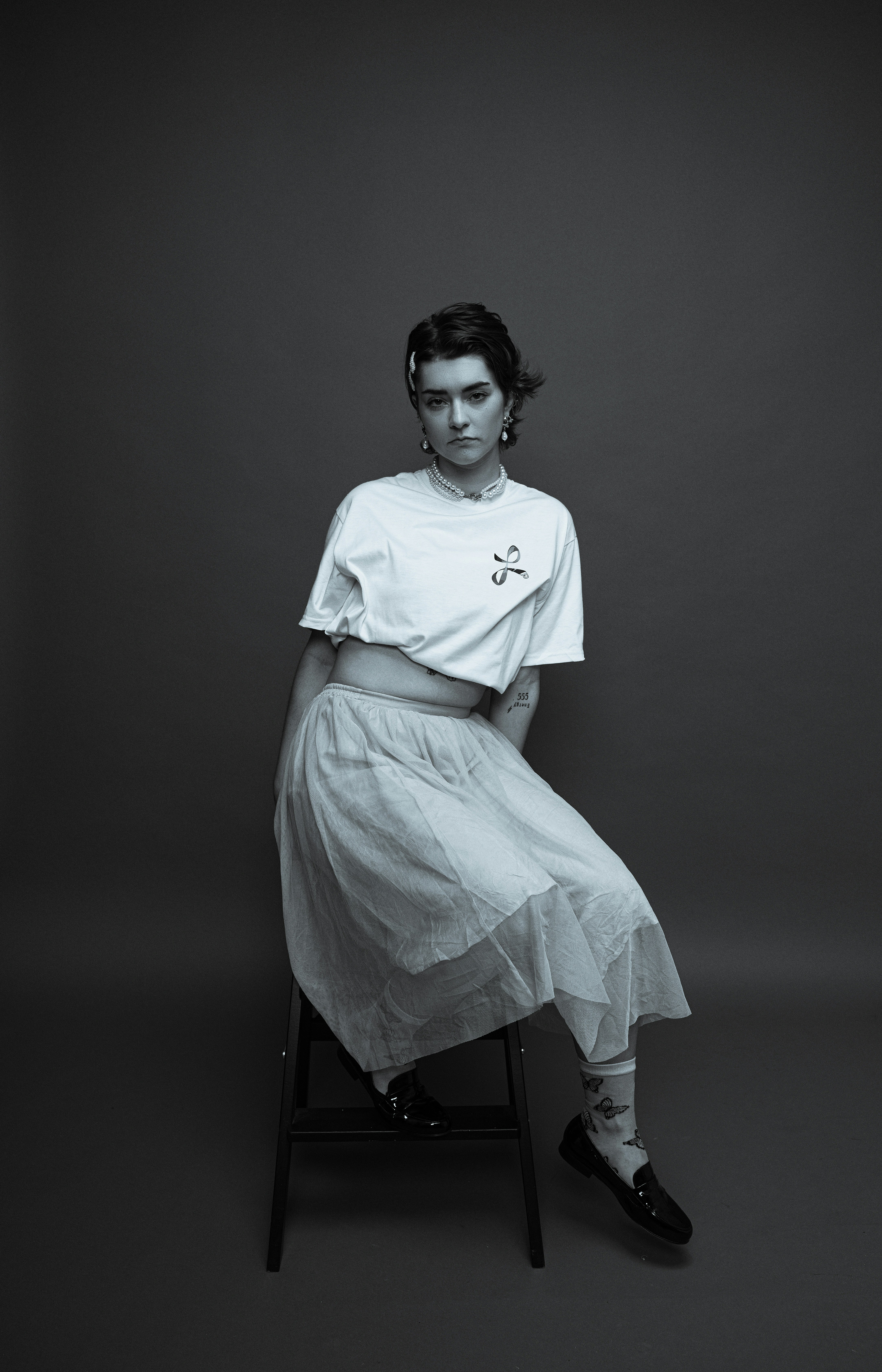 Frau im weißen T-Shirt und Rock sitzt auf einem Stuhl