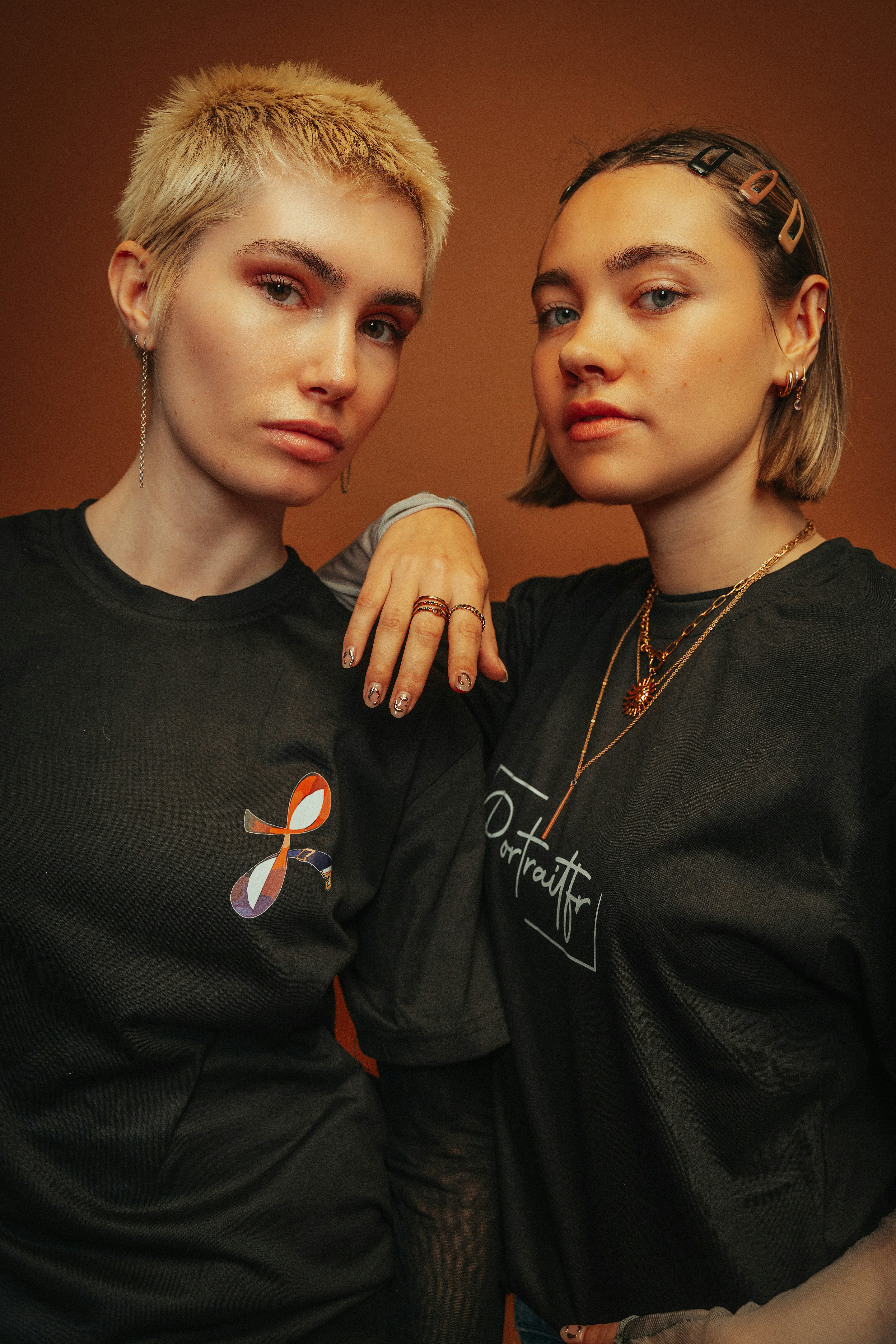 Zwei junge Frauen, die vor braunem Hintergrund posieren