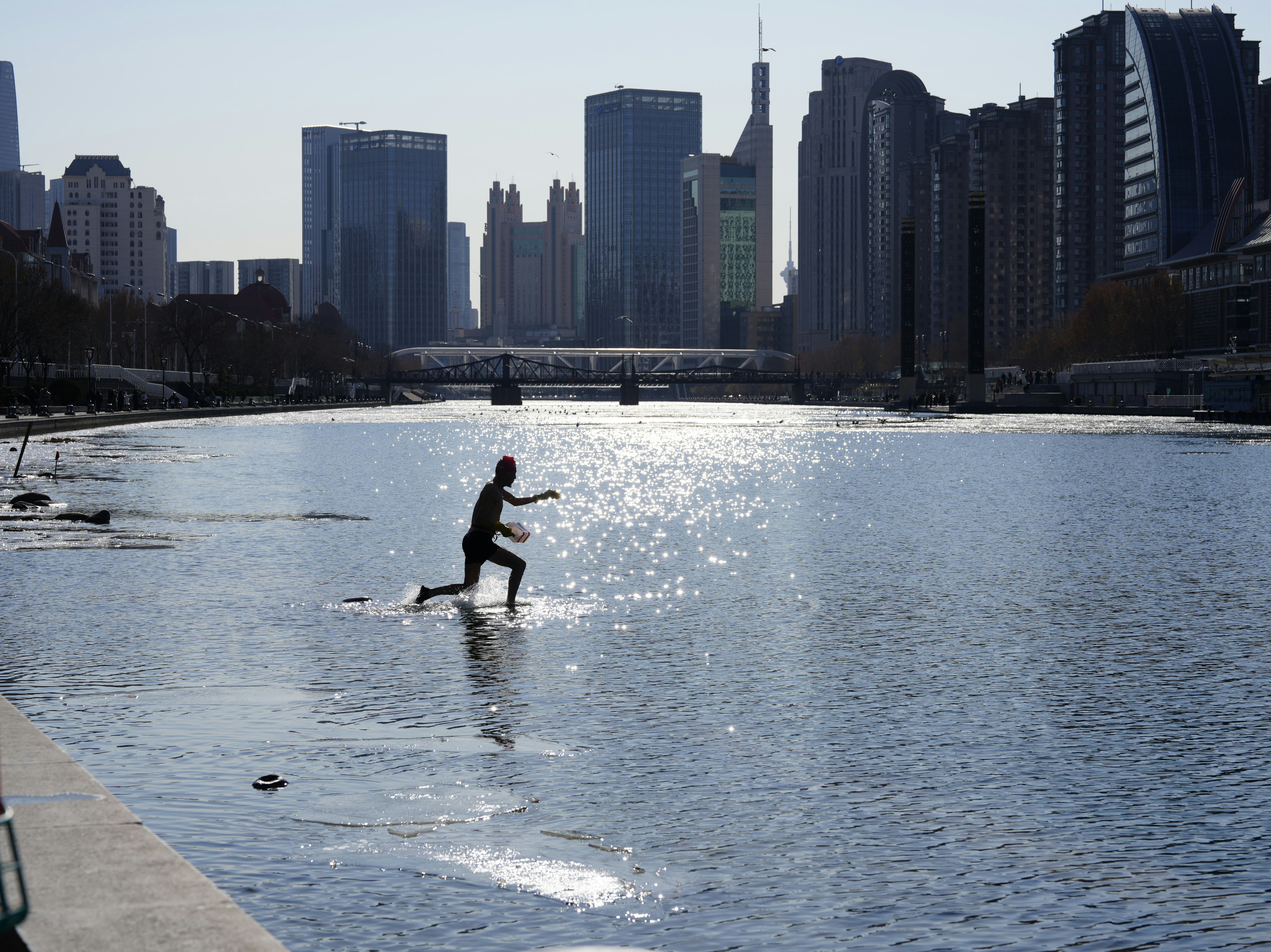 A person running through shallow water with city skyline