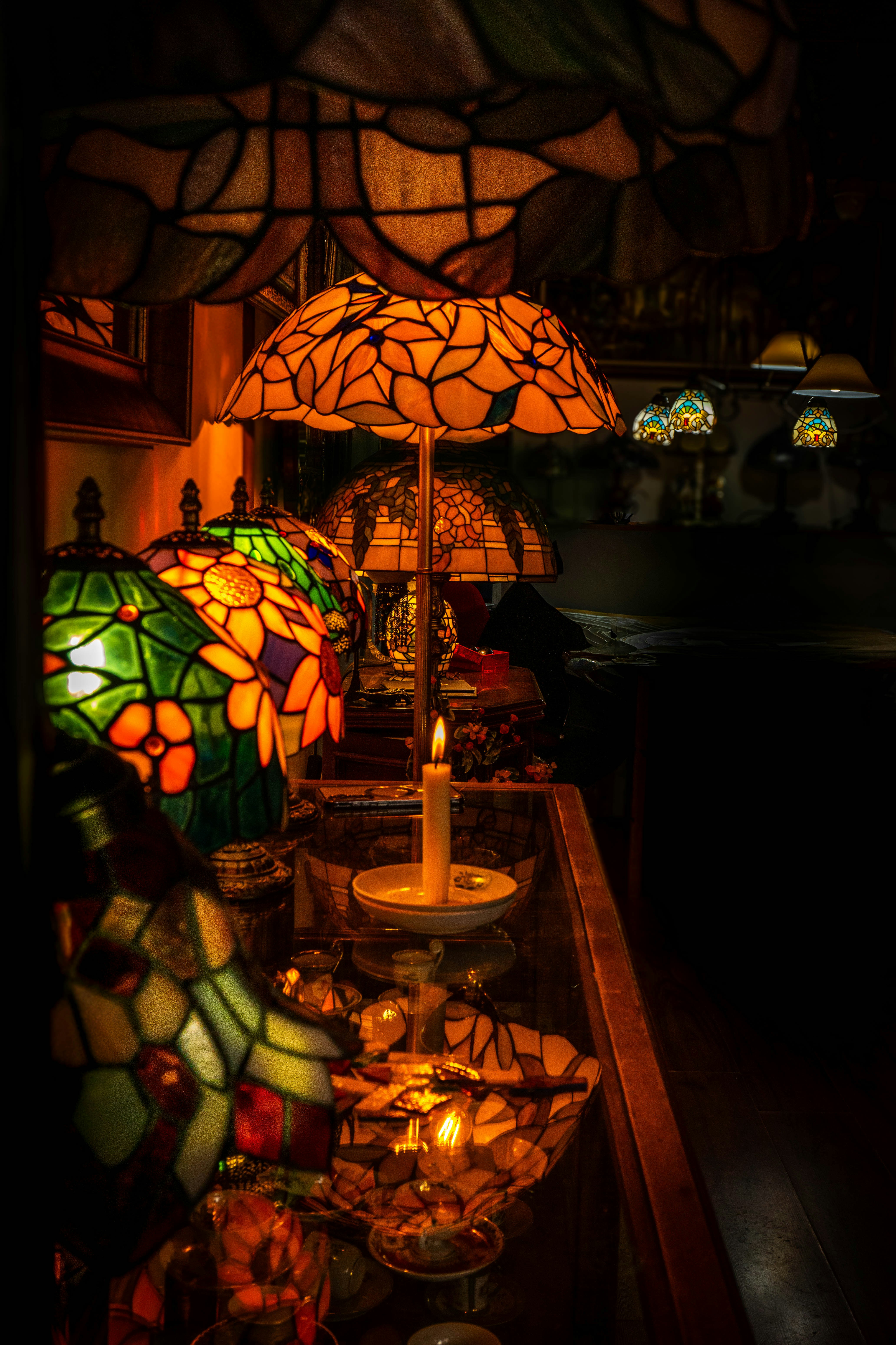 Several stained glass lamps with lit candles.
