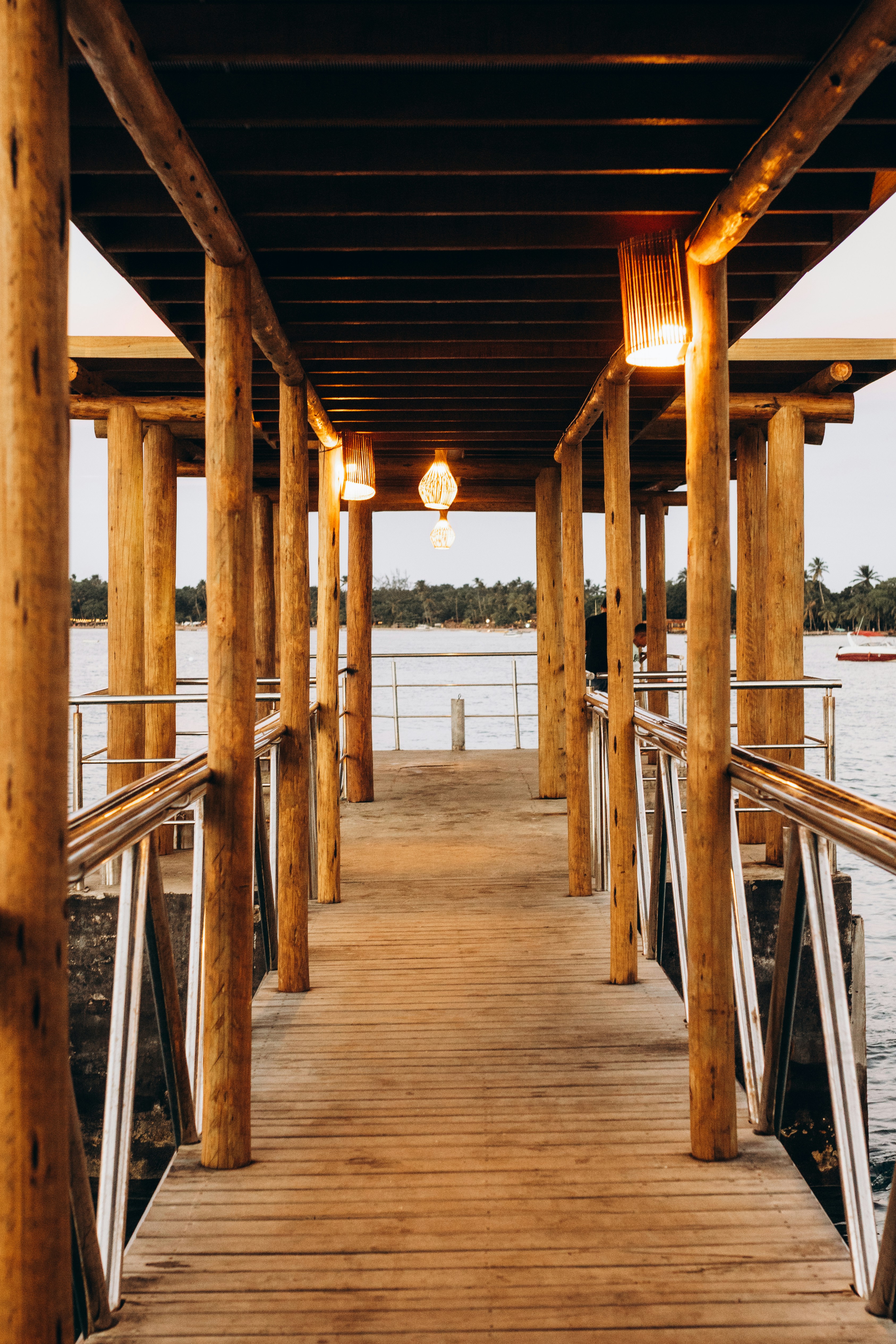 Real estate agent walking a couple down a wooden dock toward a lakefront home