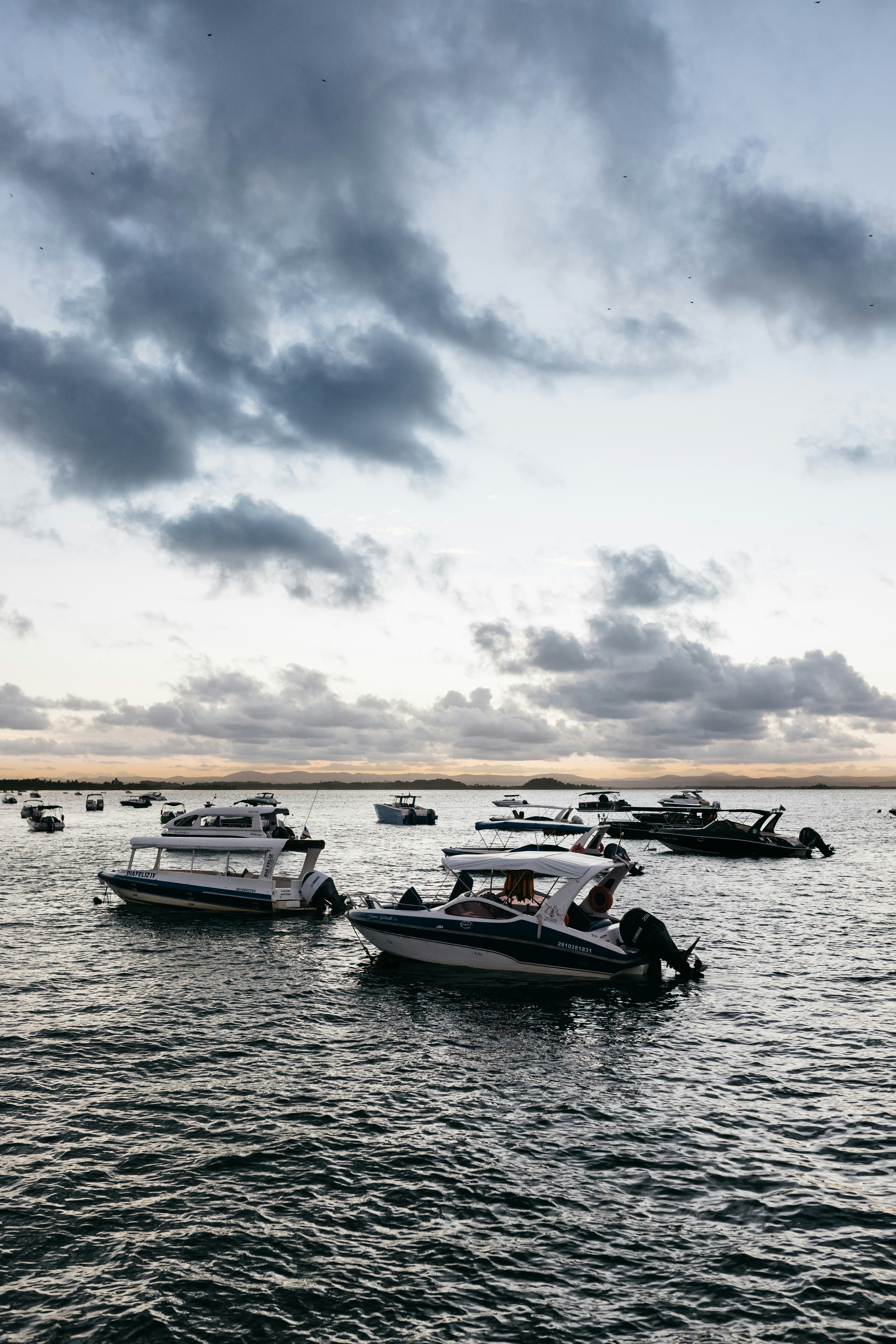 Several boats moored on the water under a cloudy sky