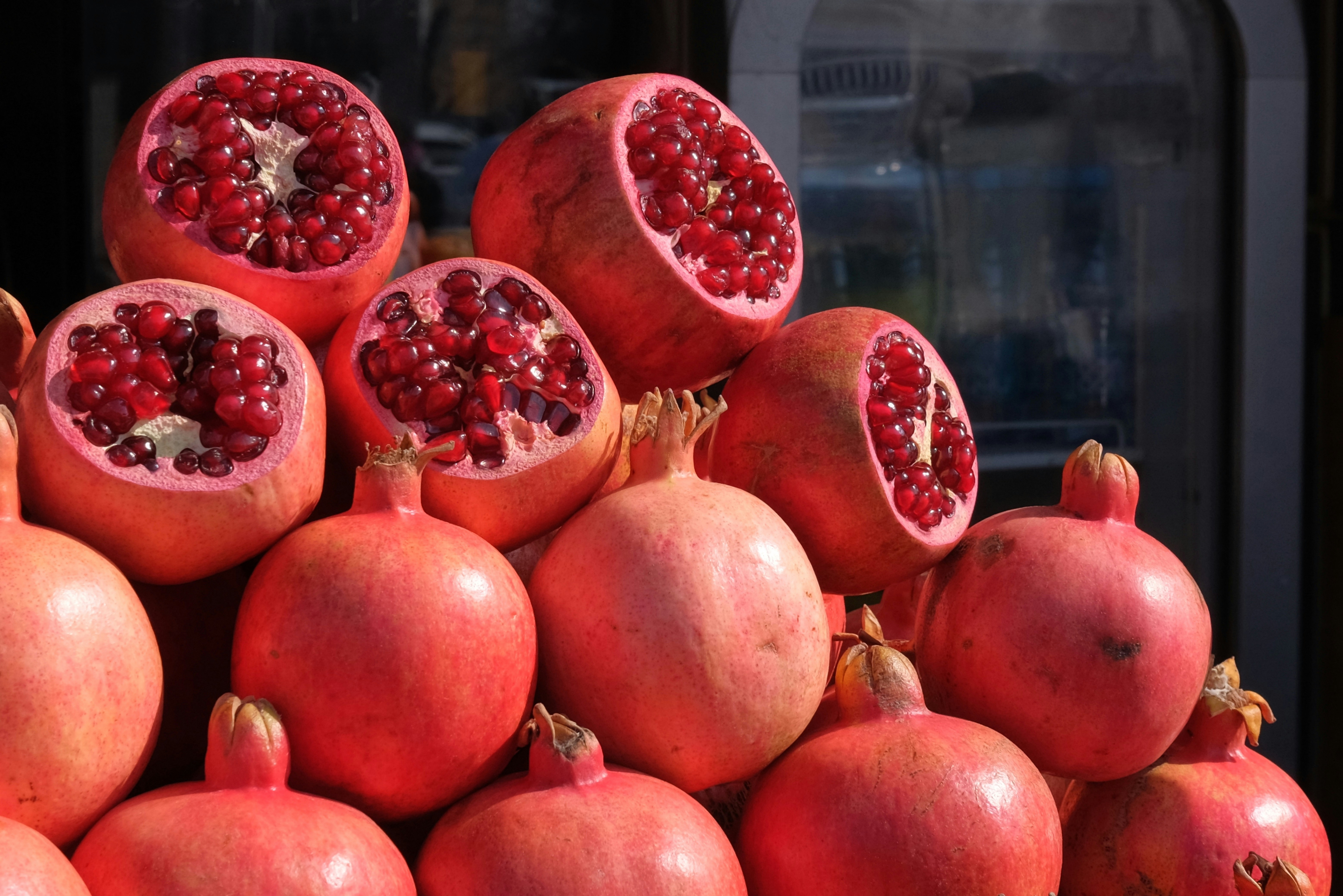 Several ripe pomegranates stacked in a market display.