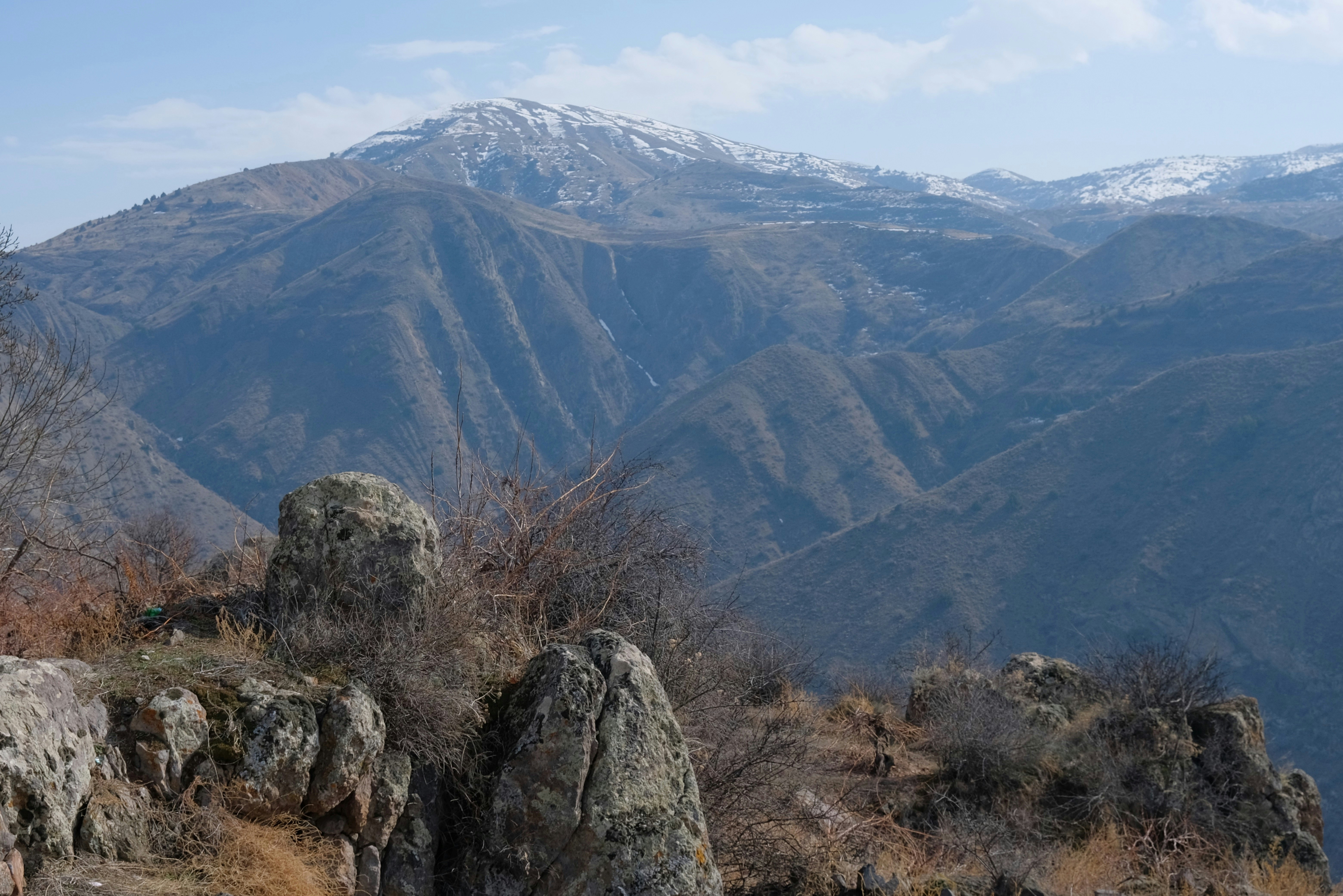 Snow-capped mountains rise above a rugged, rocky foreground.