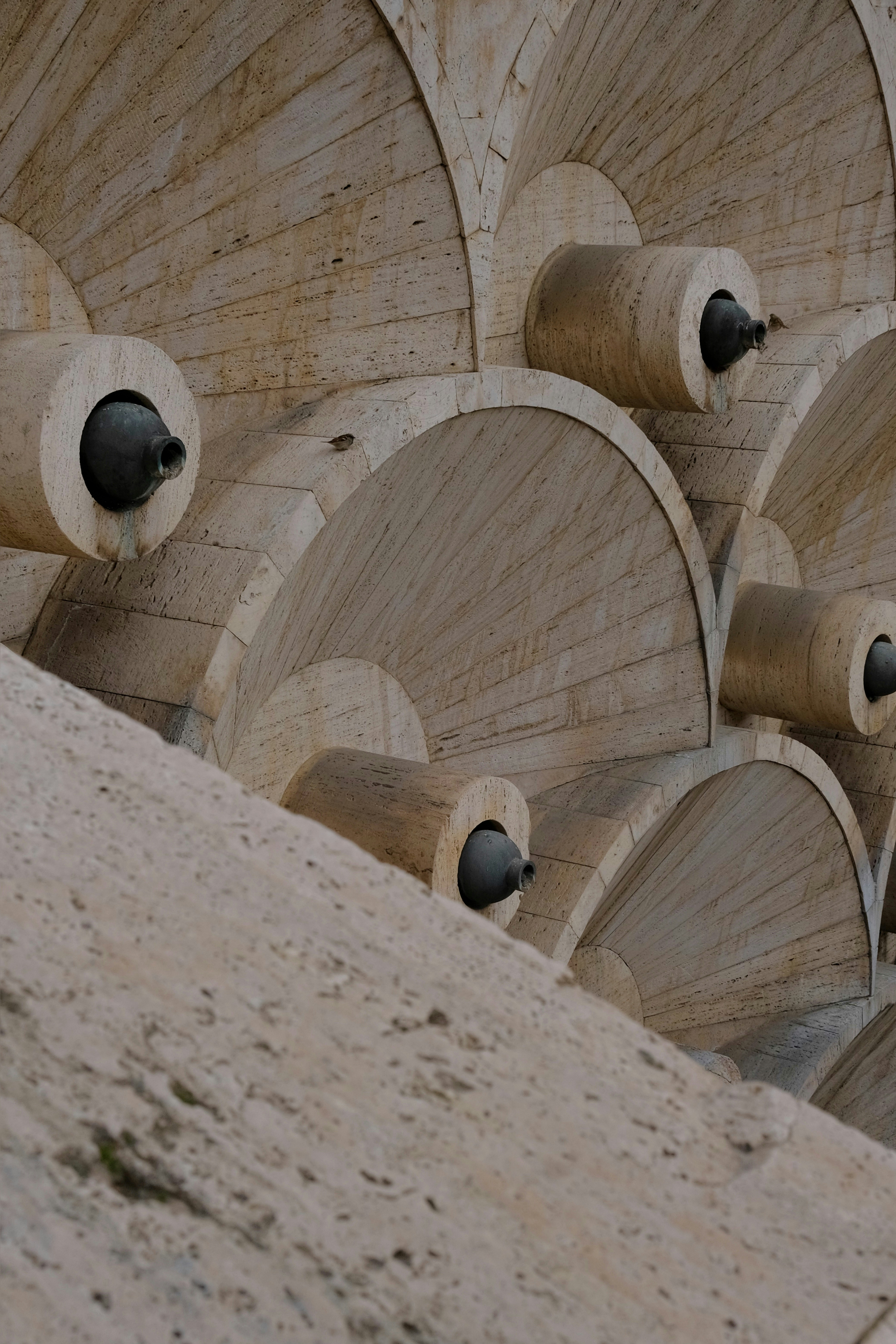 Stone fountains with cylindrical spouts arranged in arcs.