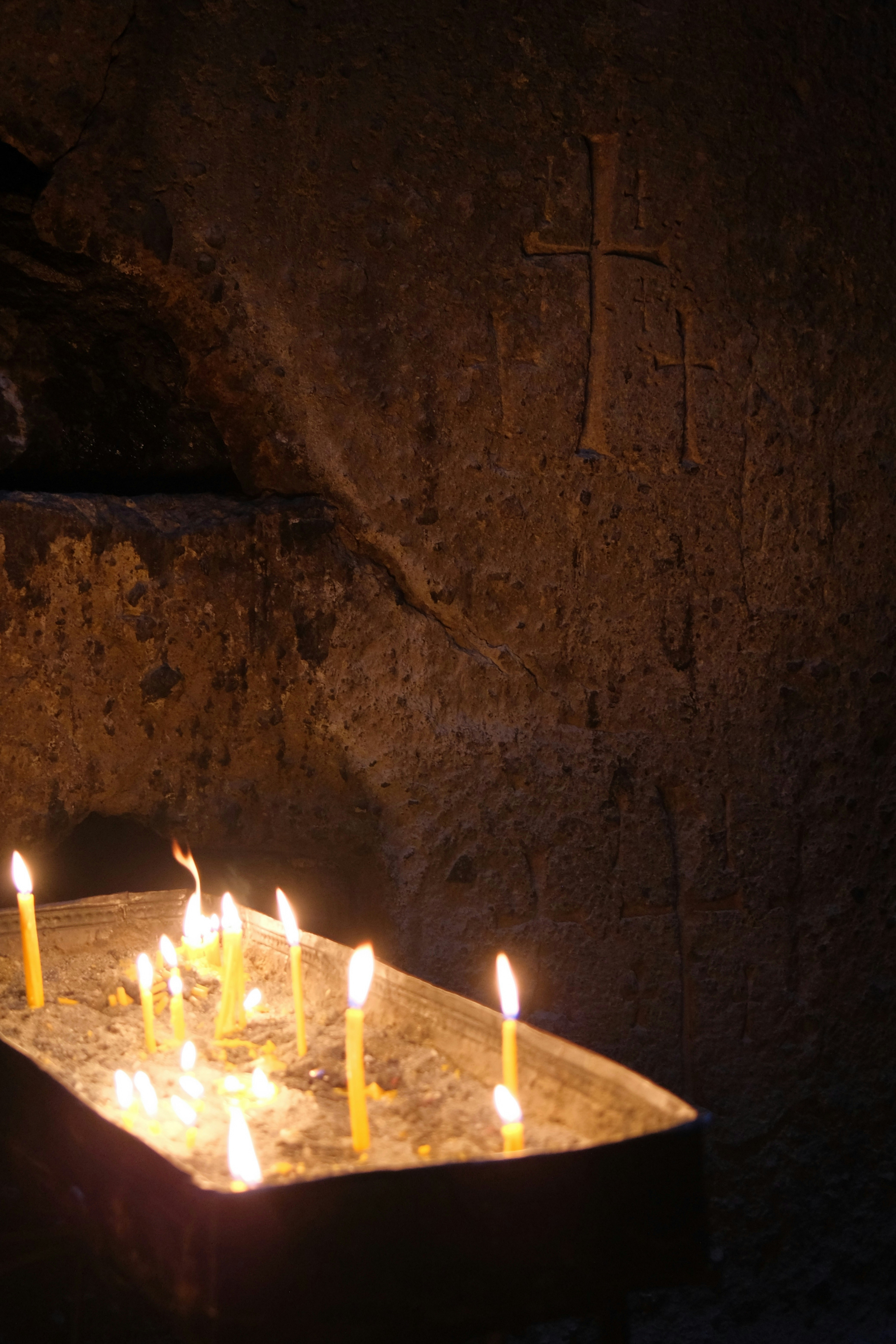 Burning candles in a dark, stone-walled room