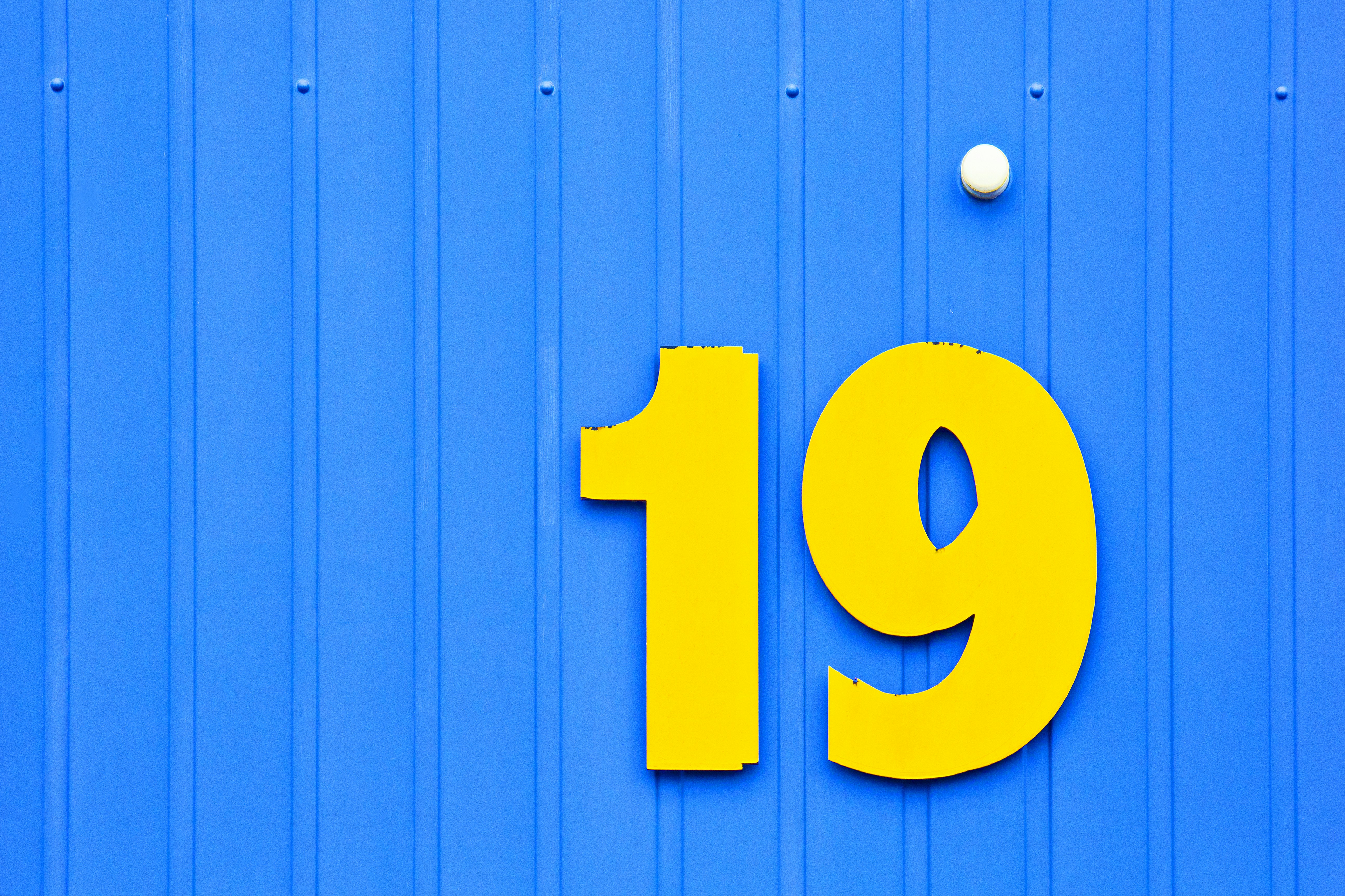 Yellow number nineteen on blue corrugated wall