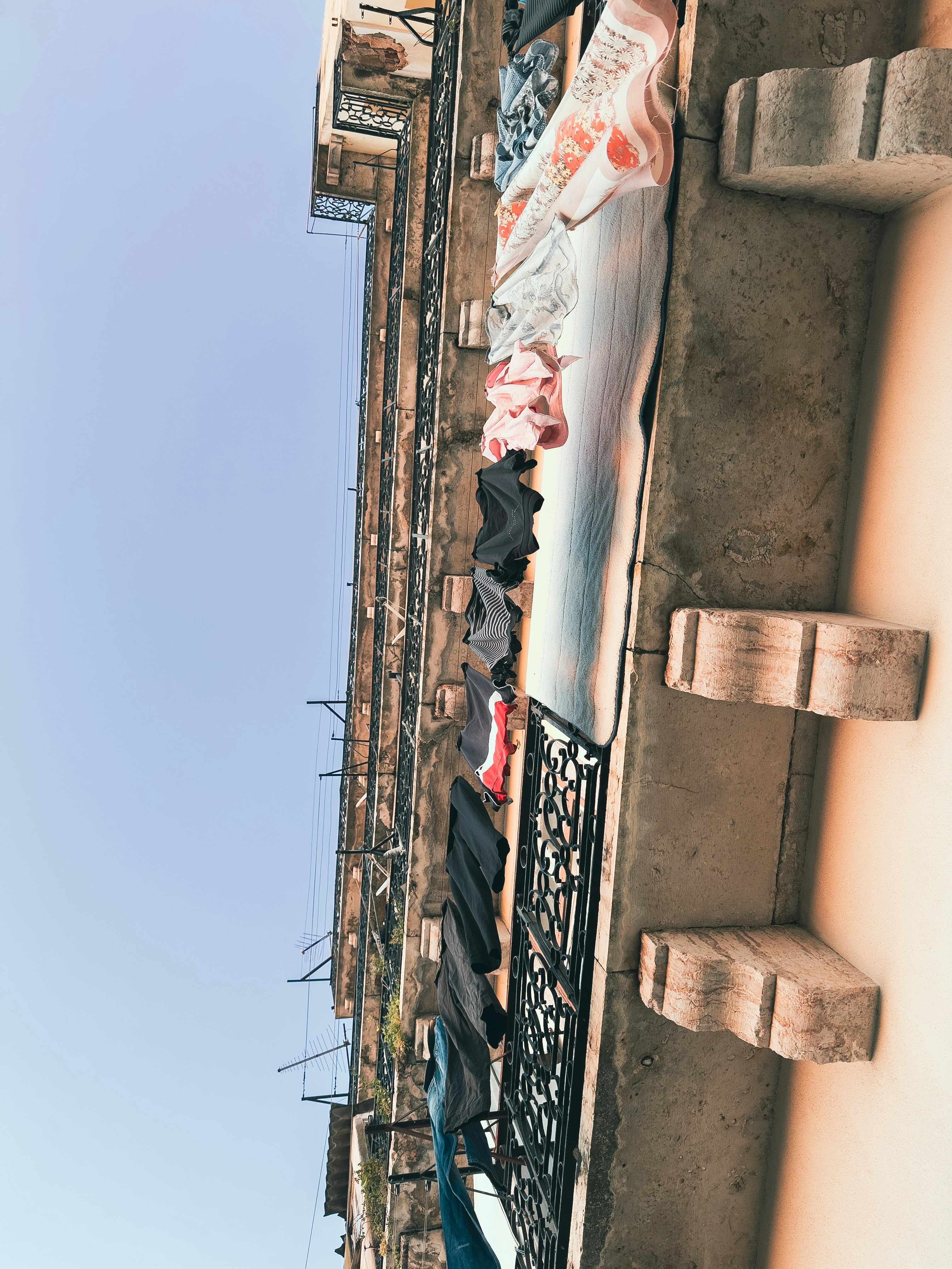 Kleidung trocknet auf einem Balkon, das gegen den blauen Himmel gelehnt ist.