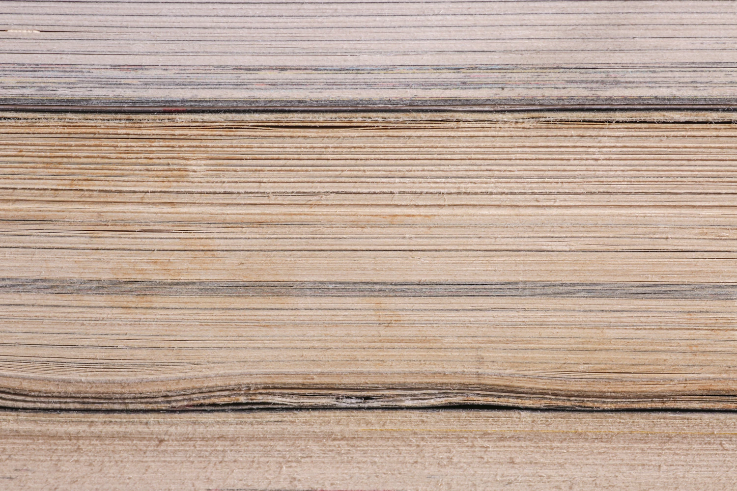A close stack of aged book pages seen from the cut edge