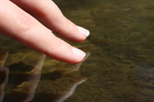 Fingers touching the surface of murky water