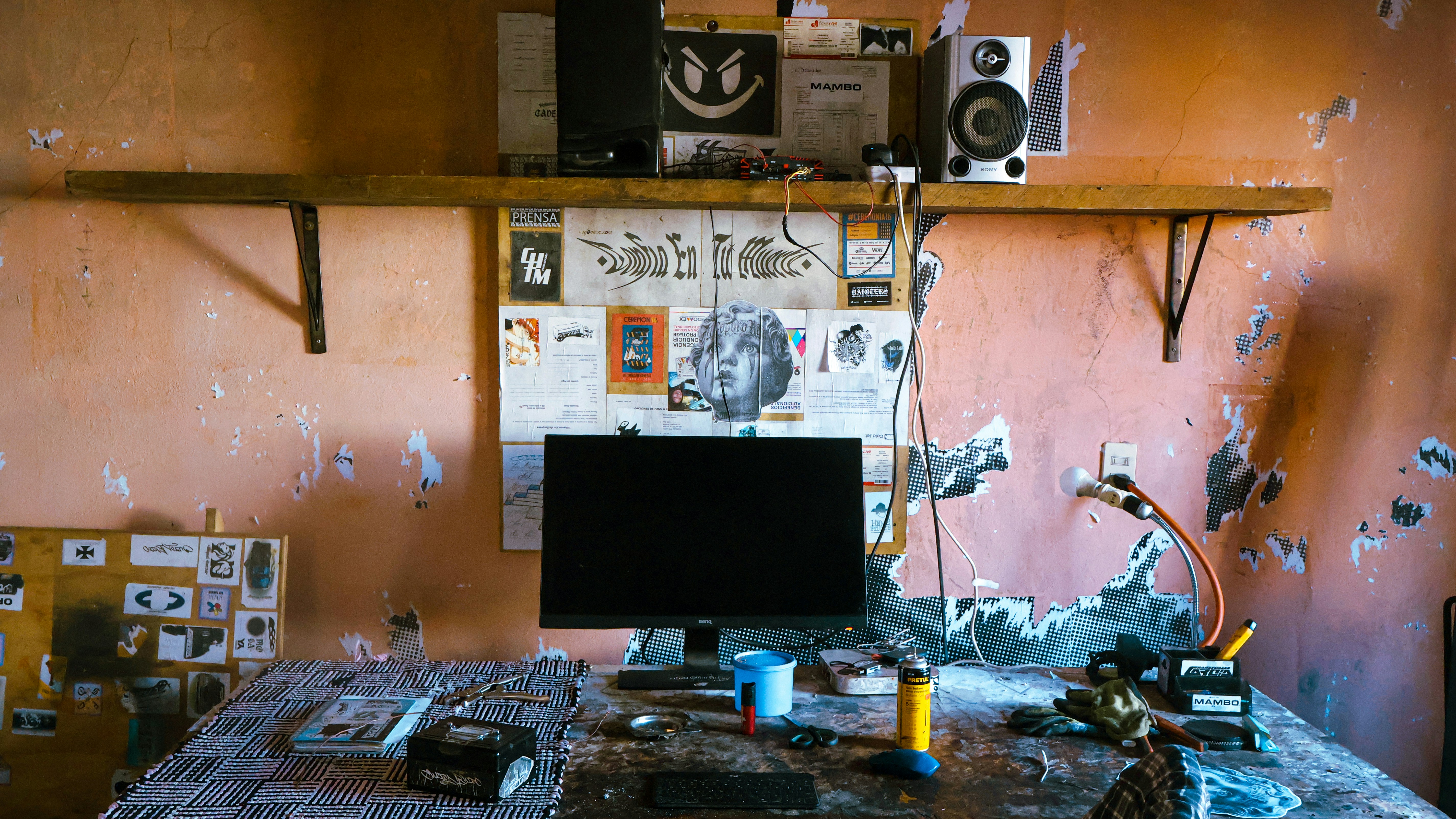 Un bureau encombré avec un écran d’ordinateur et des haut-parleurs.