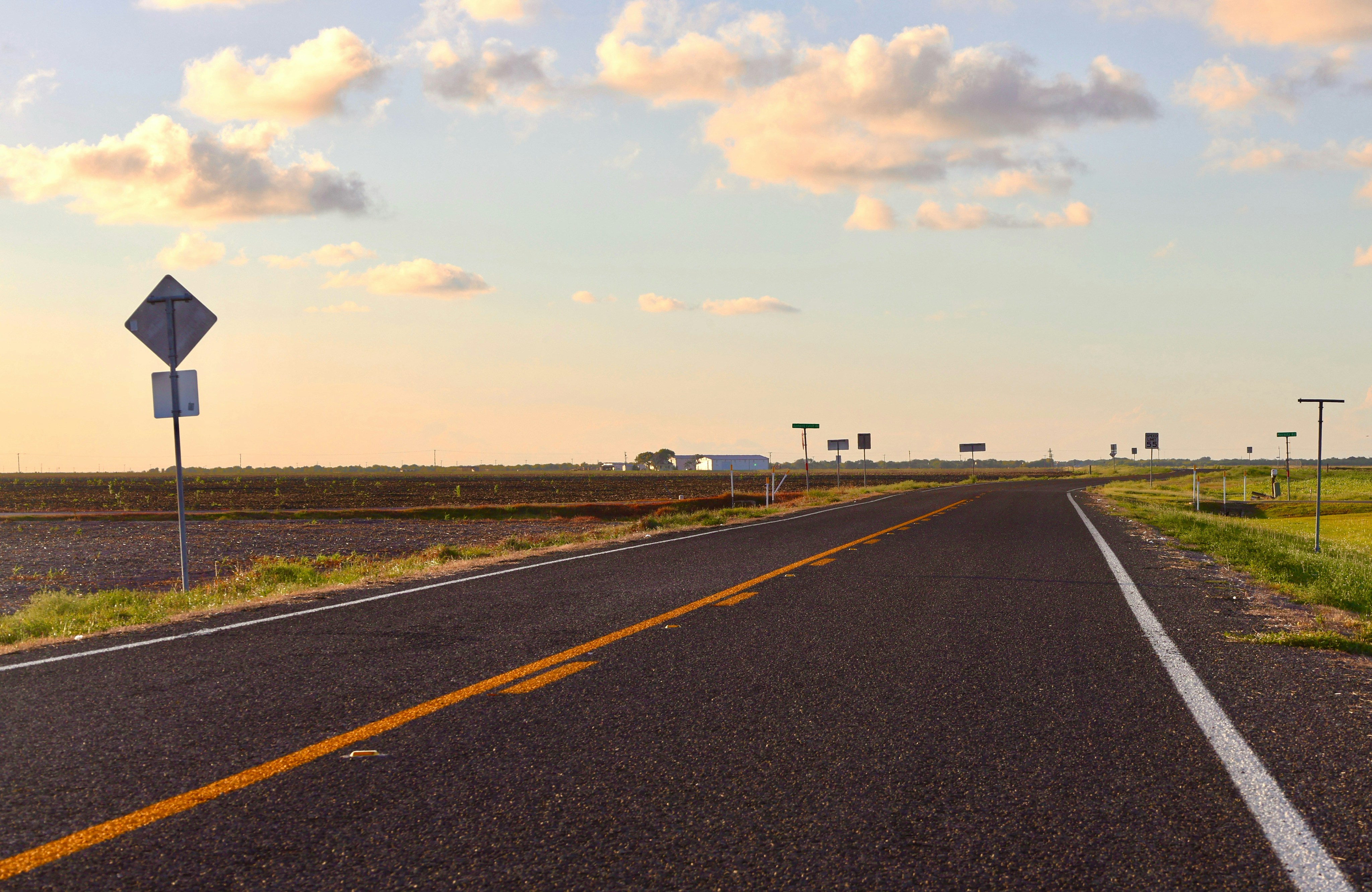 A long, empty road stretching towards the horizon at sunset.