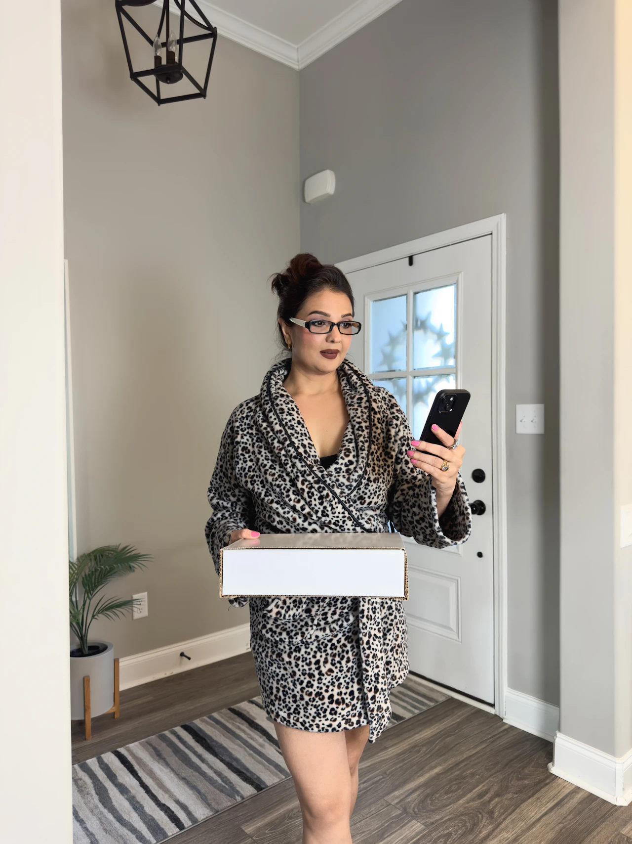 A customer taking delivery of her order at the front door while checking her phone, the last step of a remote purchase