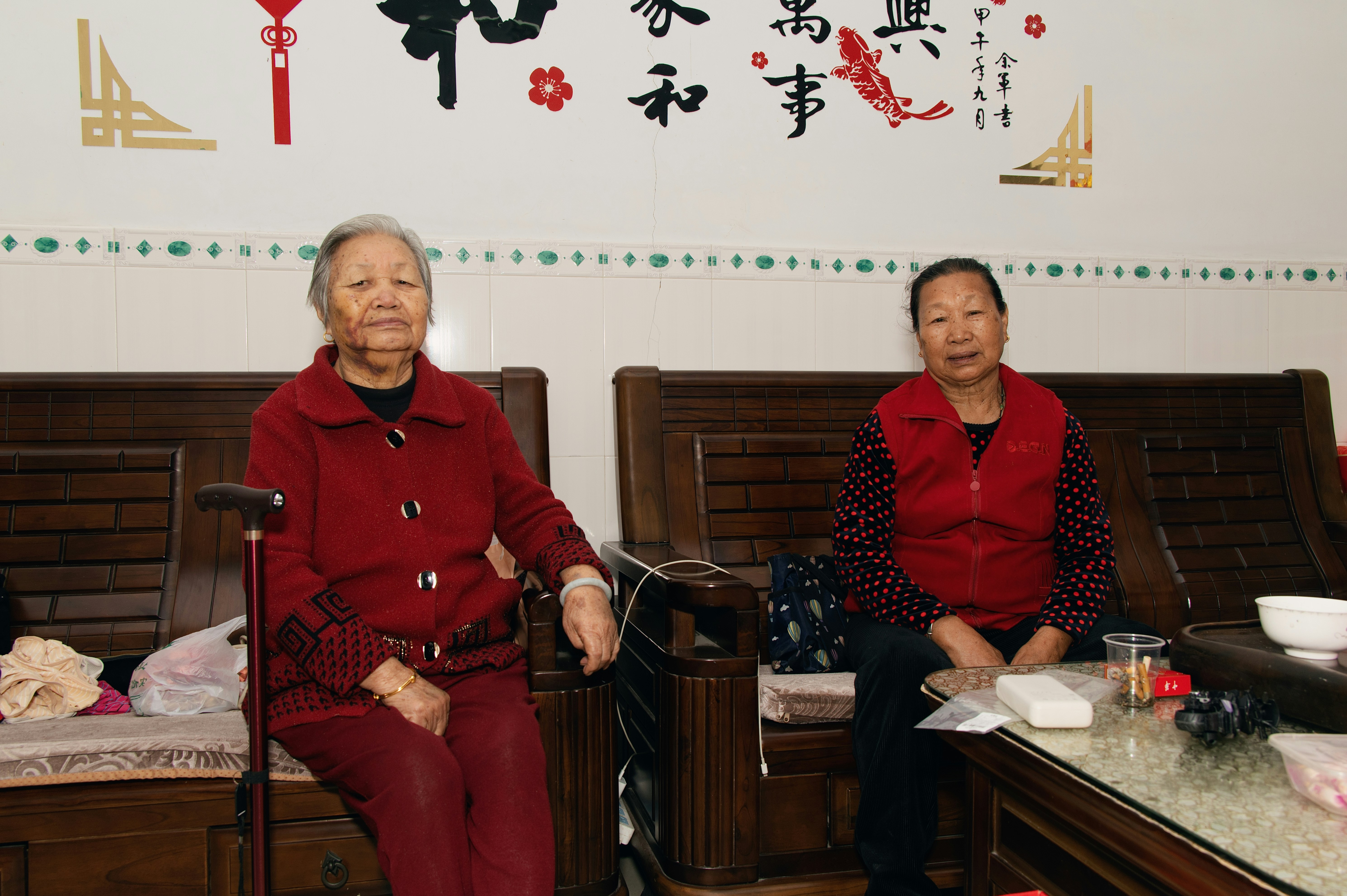 Zwei ältere Frauen sitzen auf einem Sofa drinnen.