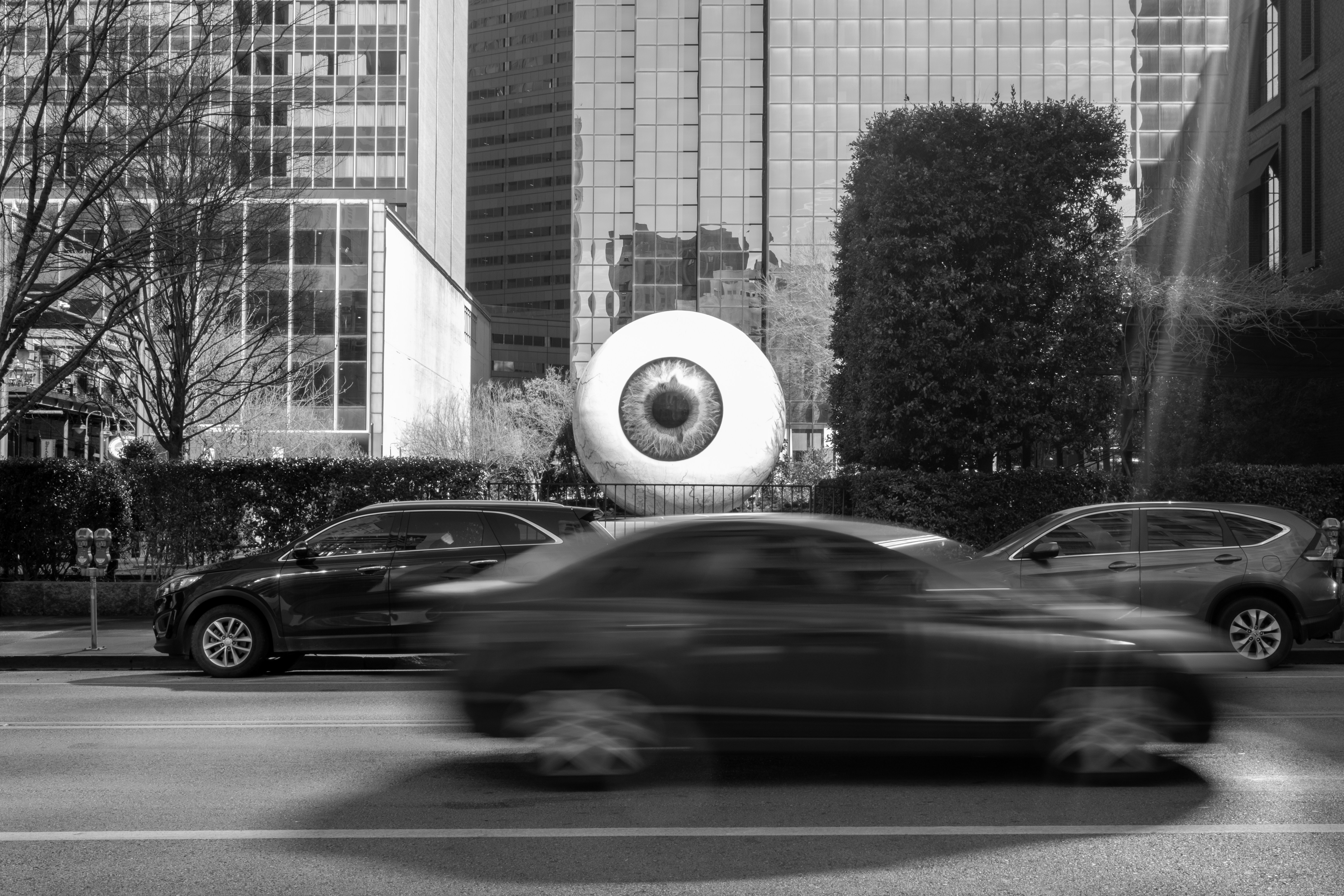 Giant eyeball sculpture on a city street with cars.