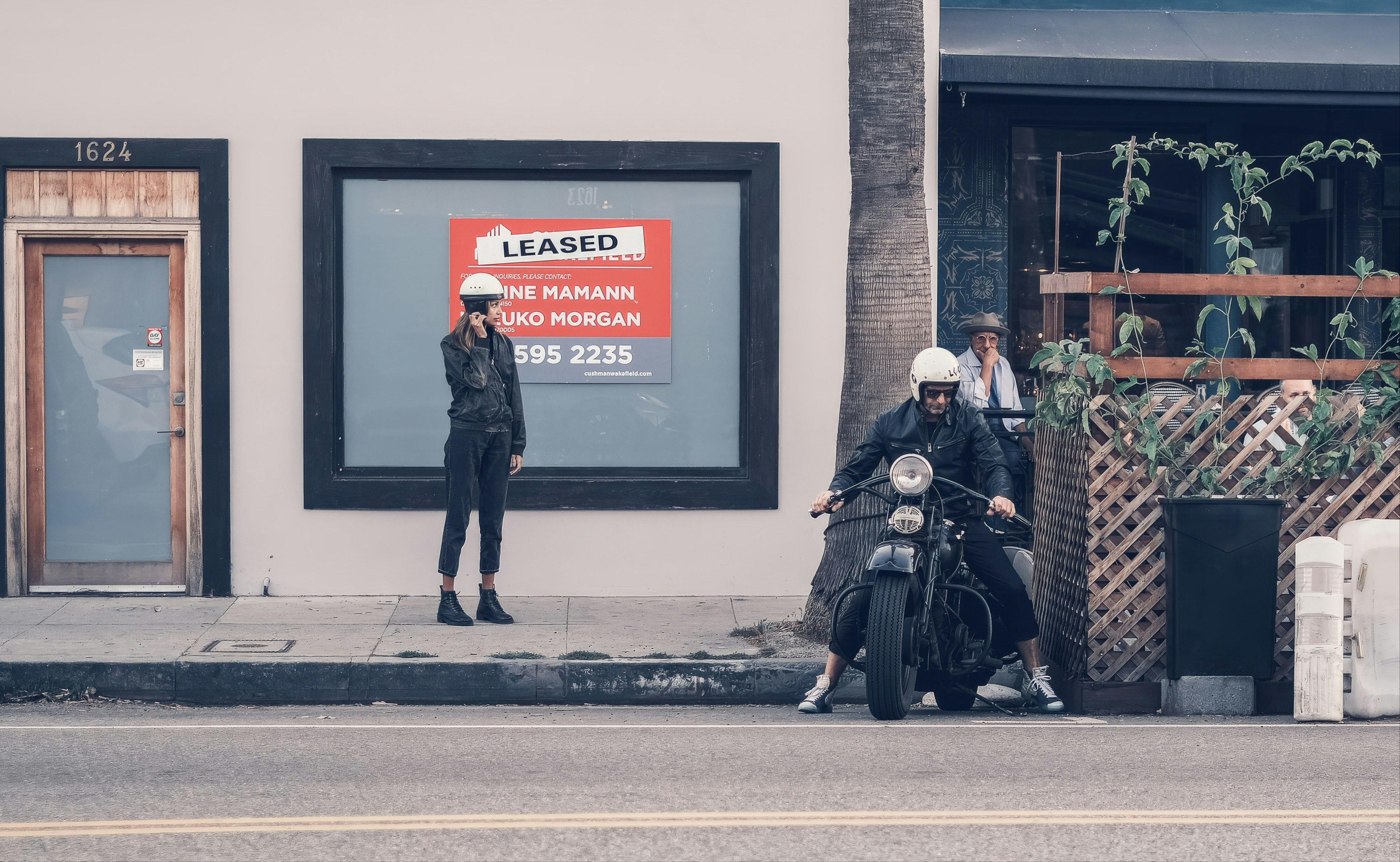Two people with helmets on motorcycles on street.