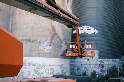 Workers paint a mural from a cherry picker