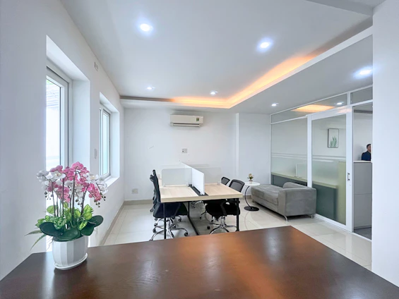 Modern office space with desks, chairs, and sofa.