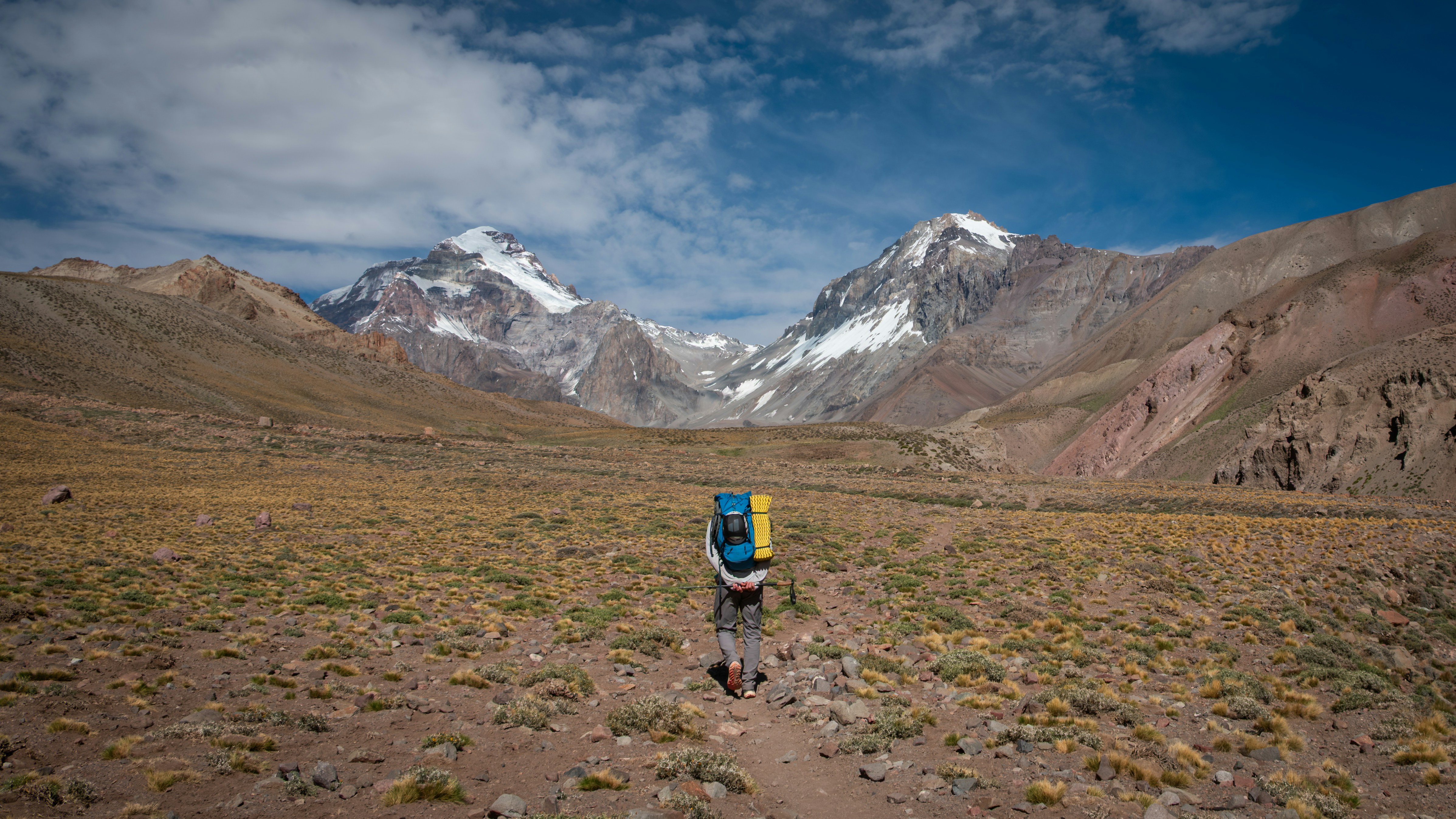 Un randonneur marche vers de majestueuses montagnes enneigées