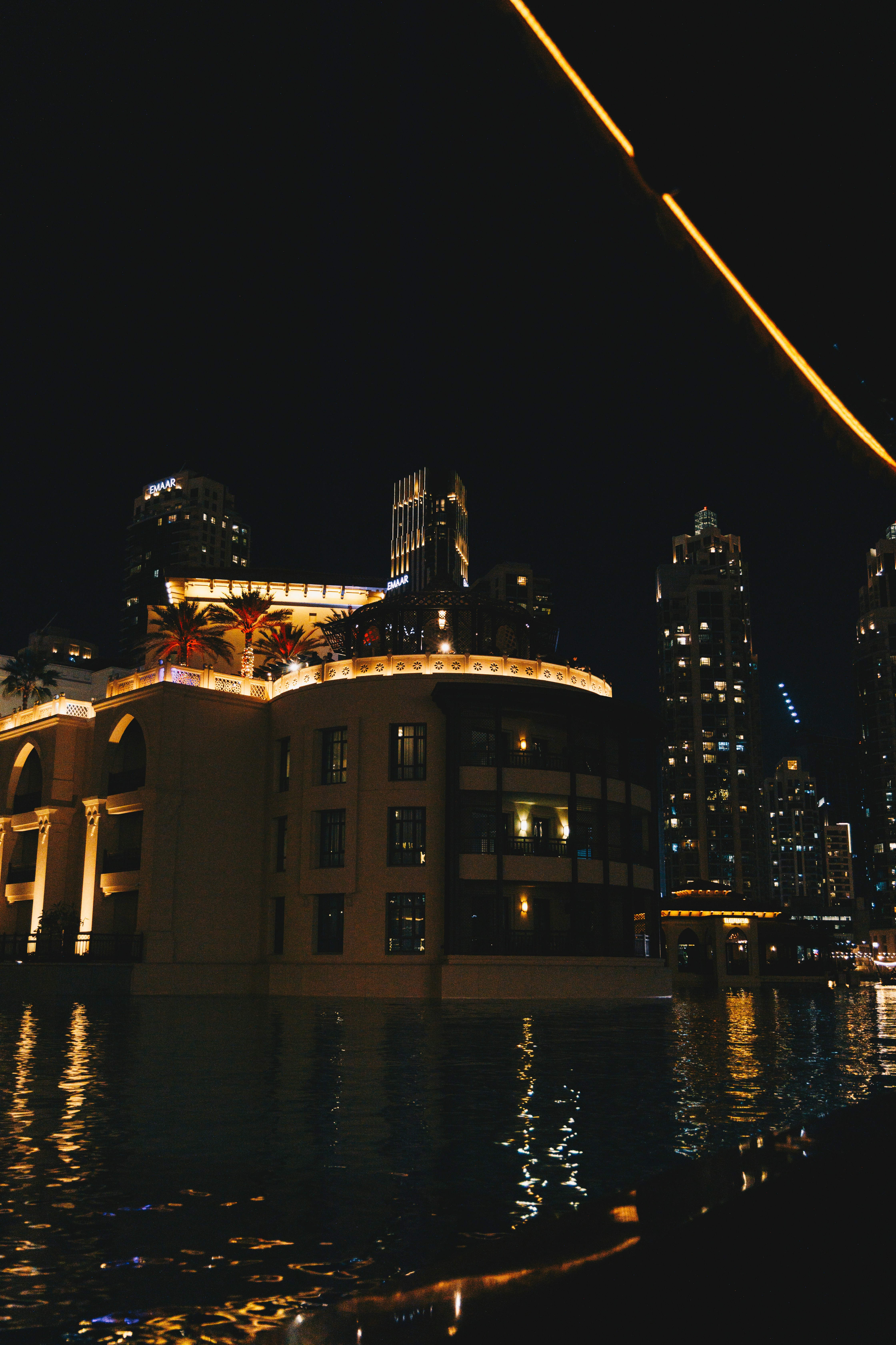 Modern buildings with lights reflecting on water at night.