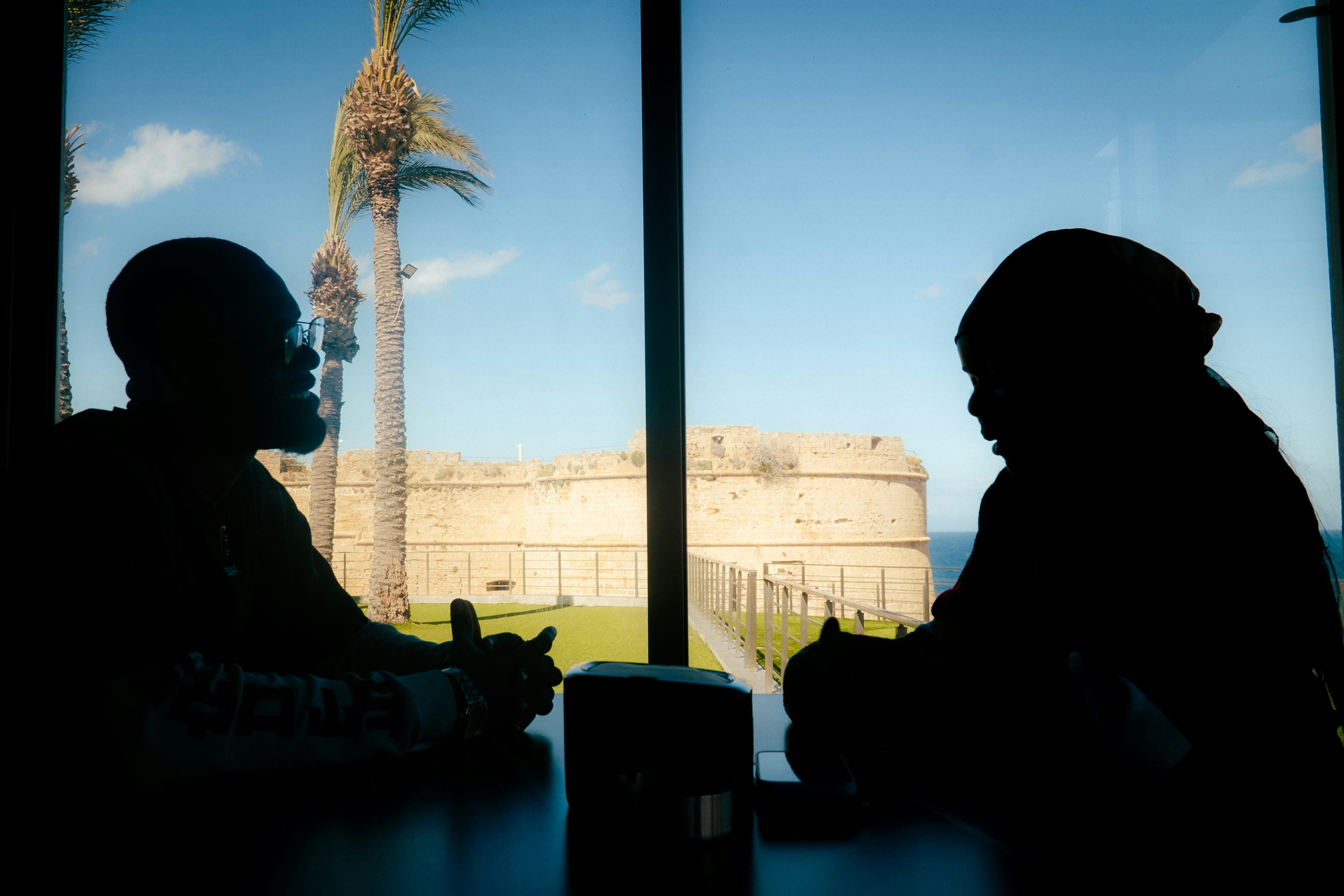 Dua orang bersiluet di meja yang menghadap ke kastil.