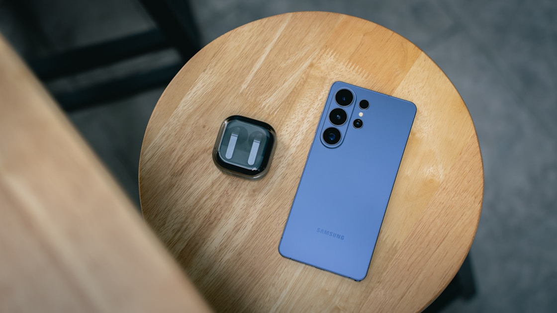 Smartphone dengan TWS earbuds wireless dan case di atas meja minimalis