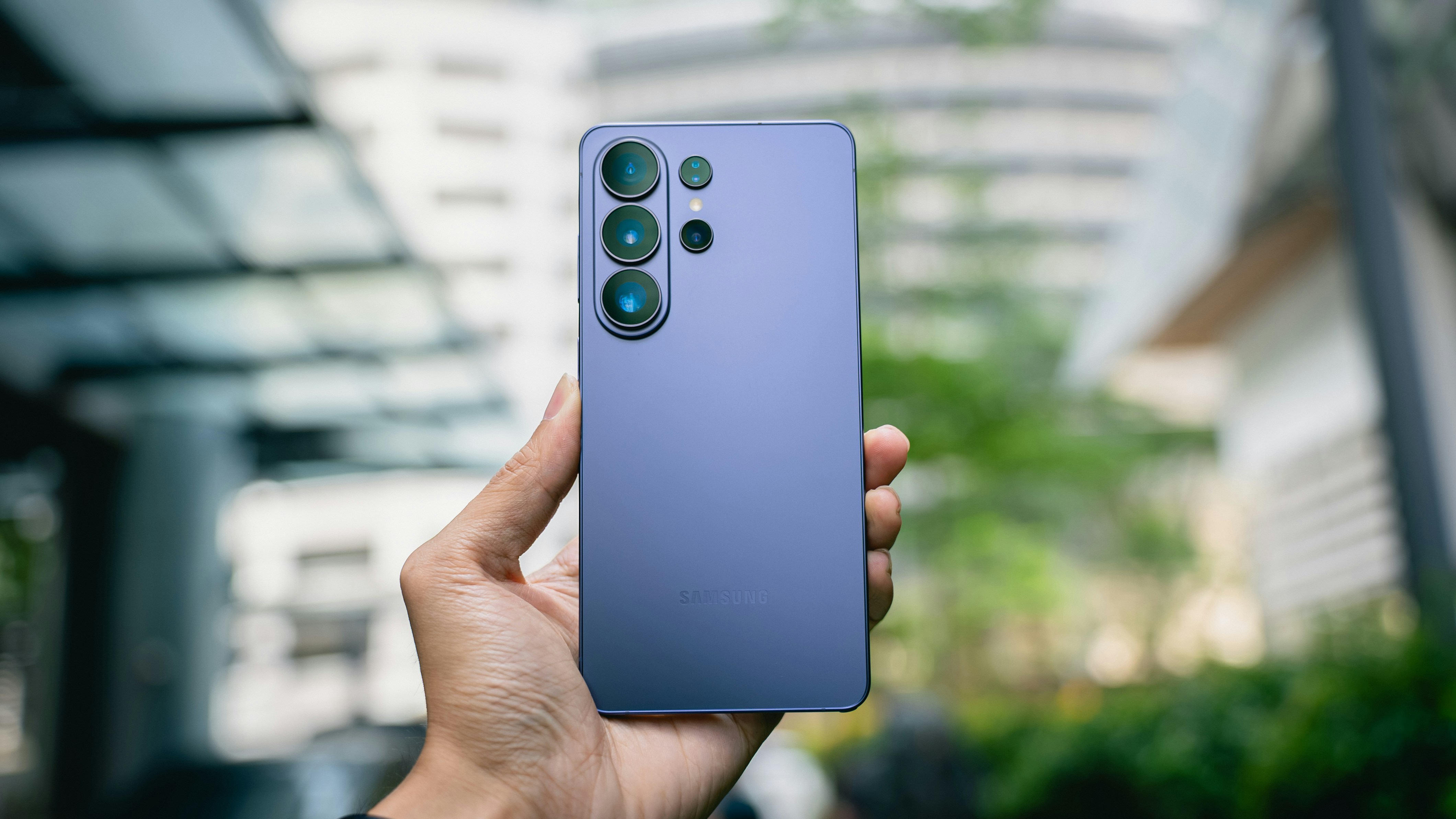 Hand holding a purple smartphone with multiple cameras.