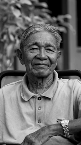 Elderly asian man smiling in black and white.