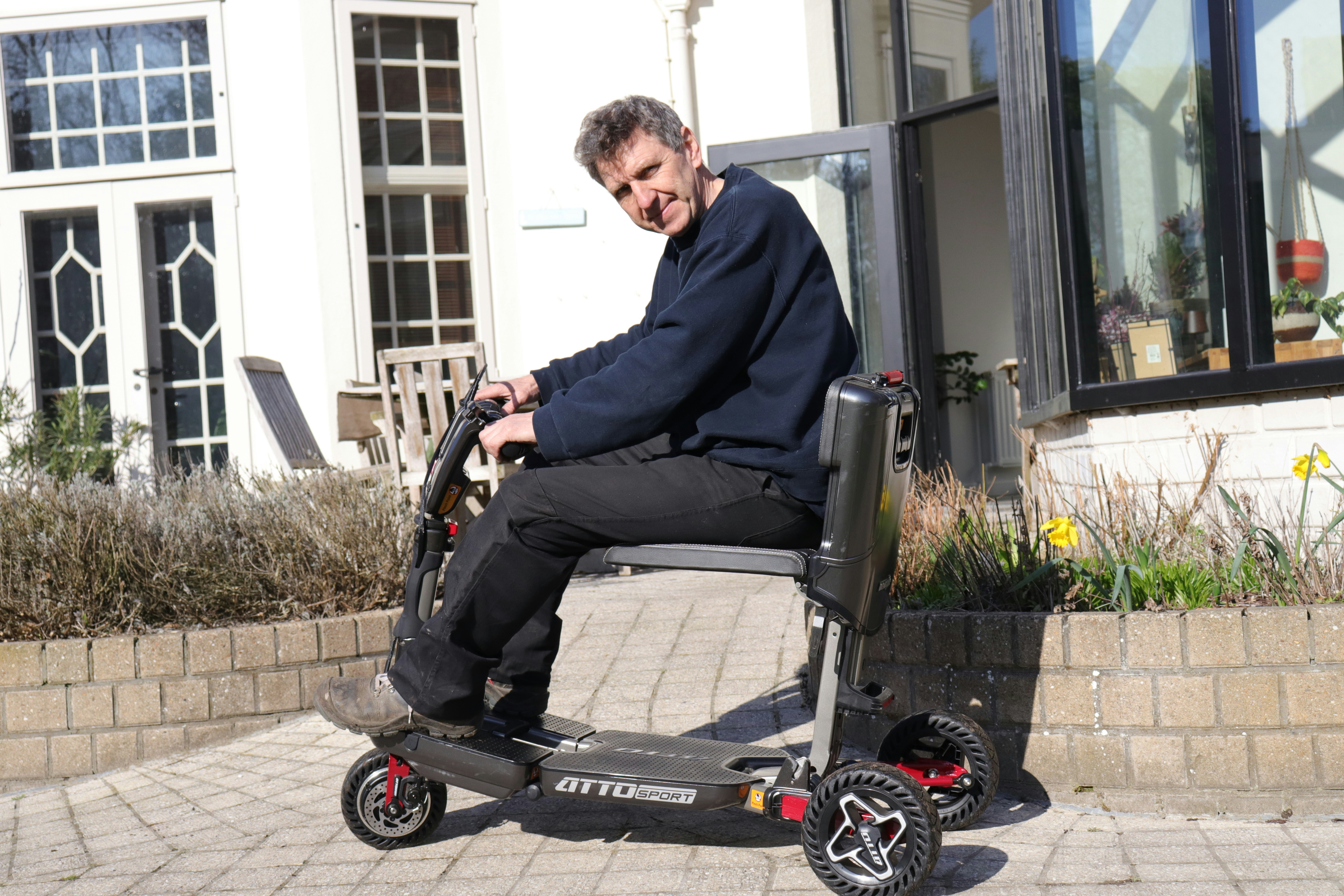 Man riding a mobility scooter outside a building.