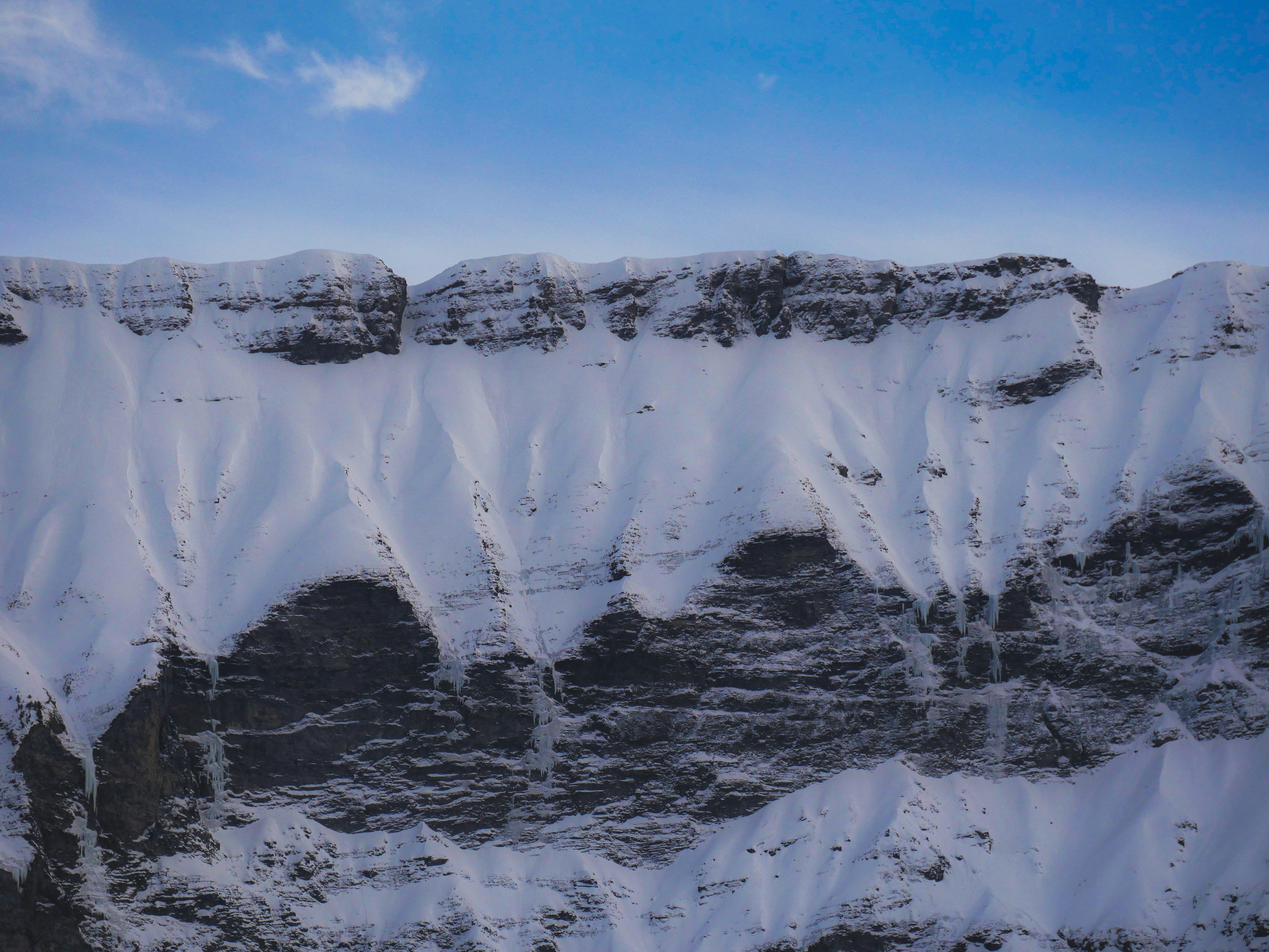 Snow-covered mountain cliffs under a clear blue sky
