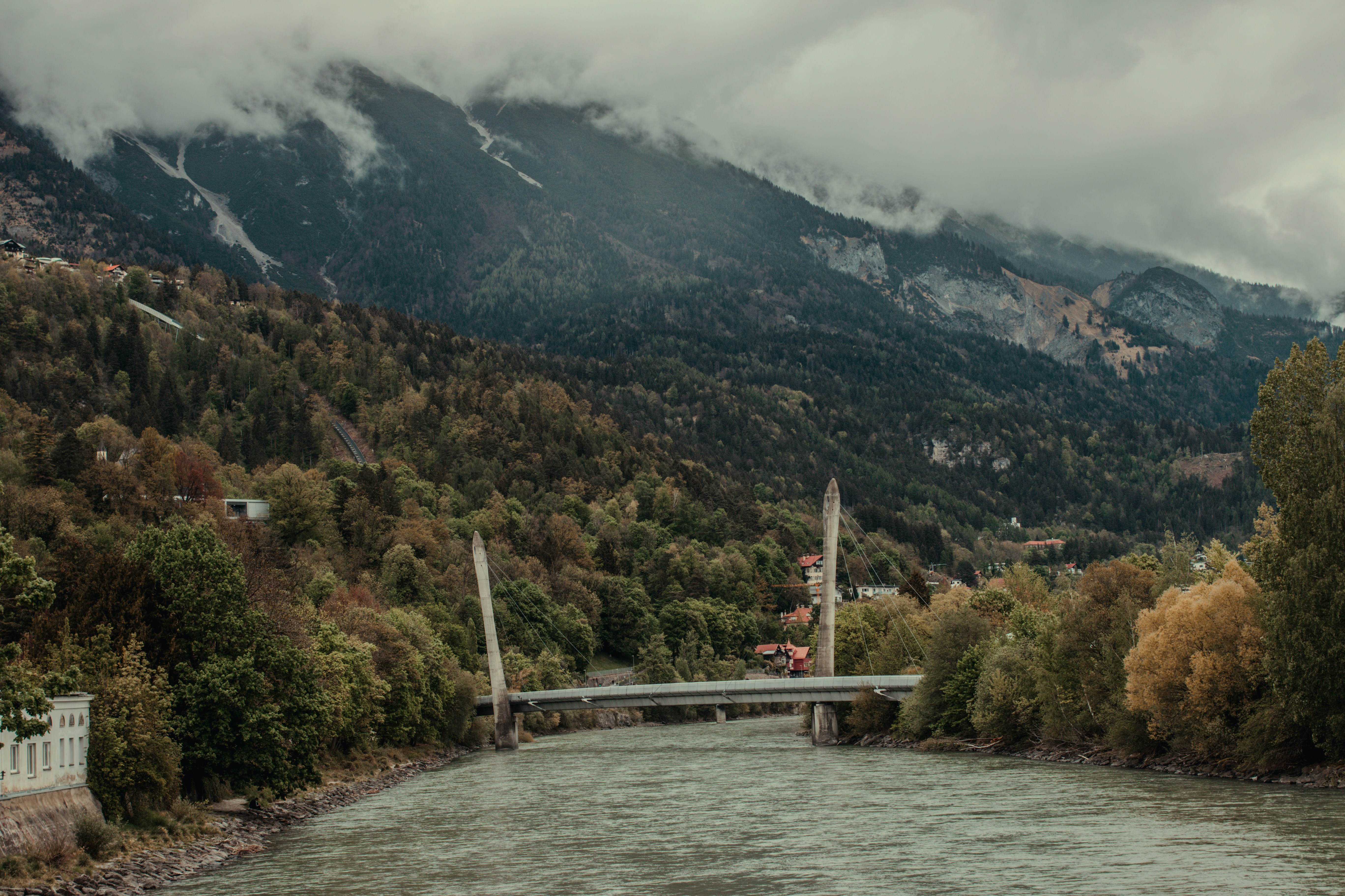 A bridge spans a river with mountains in the background.