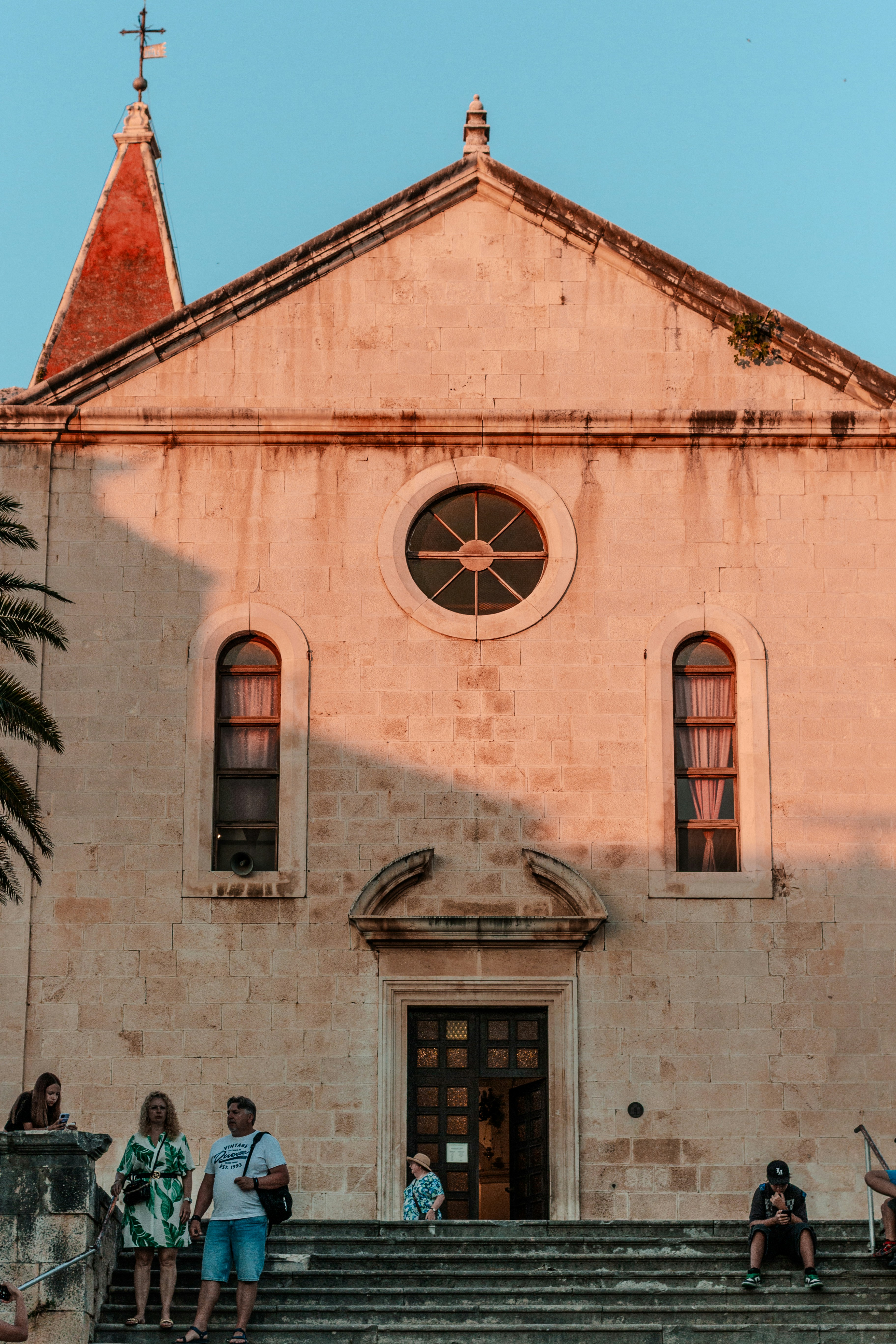 People on steps of a stone church at sunset - religious history sites
