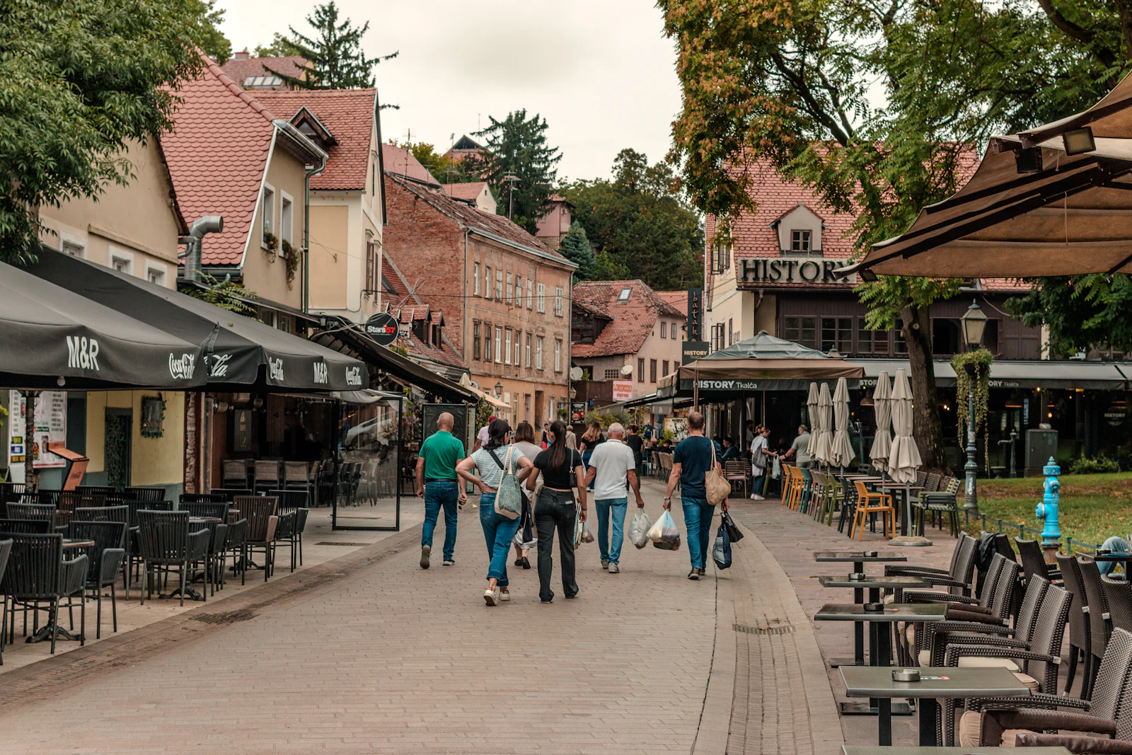 People walking down a European street lined with outdoor cafes