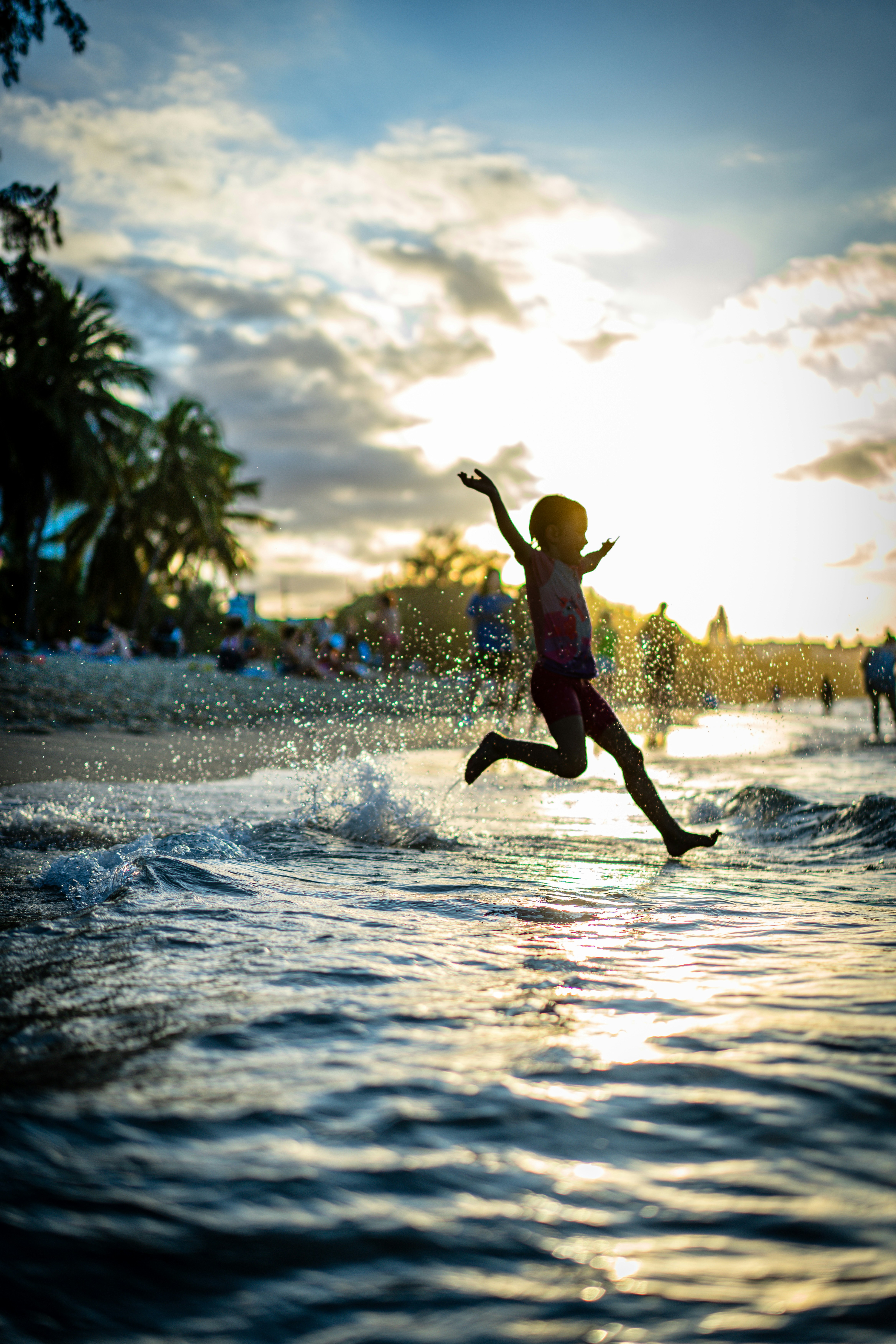 Child splashes in ocean waves at sunset