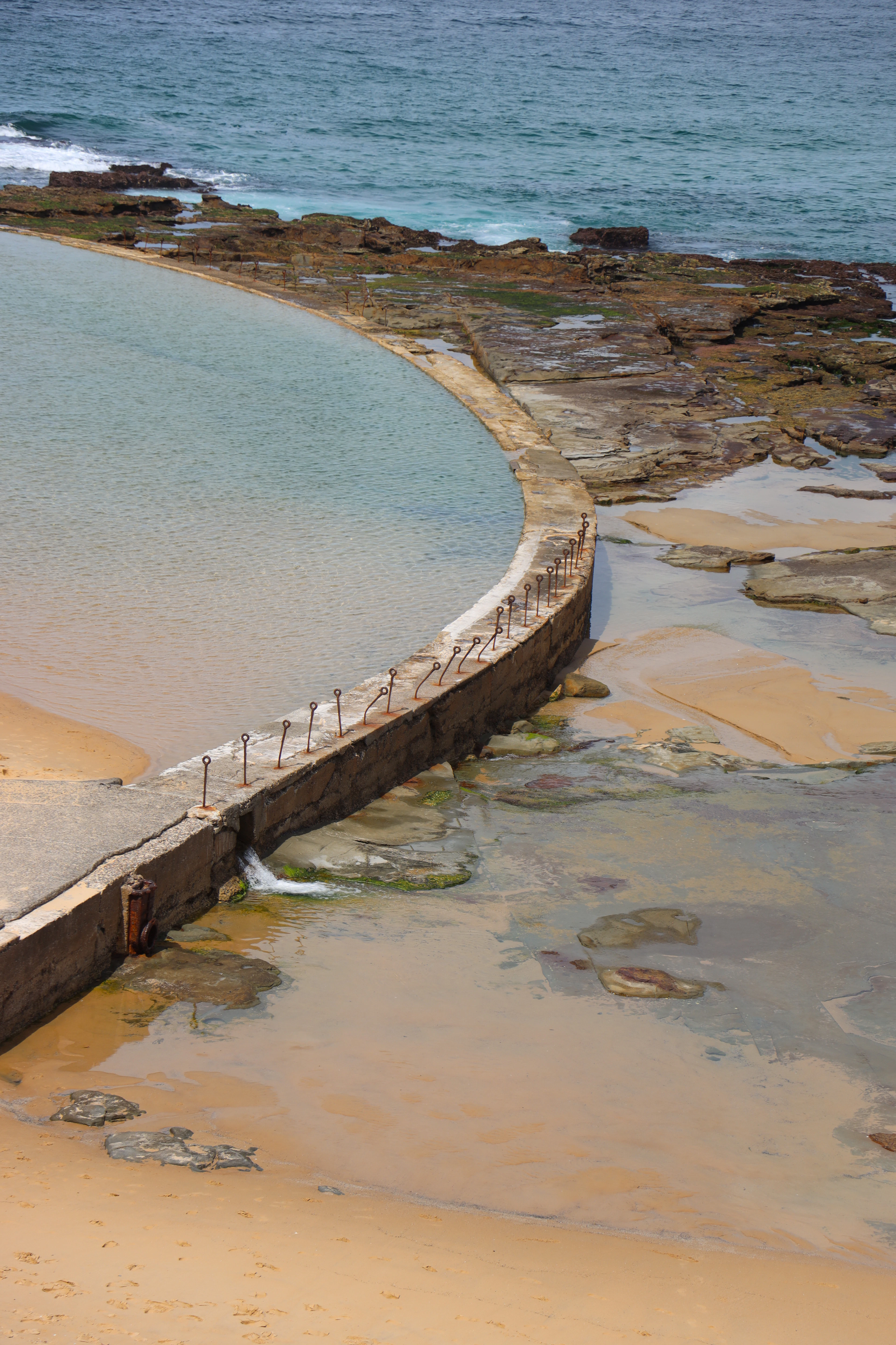 Natural rock pool between sand and rocky shore